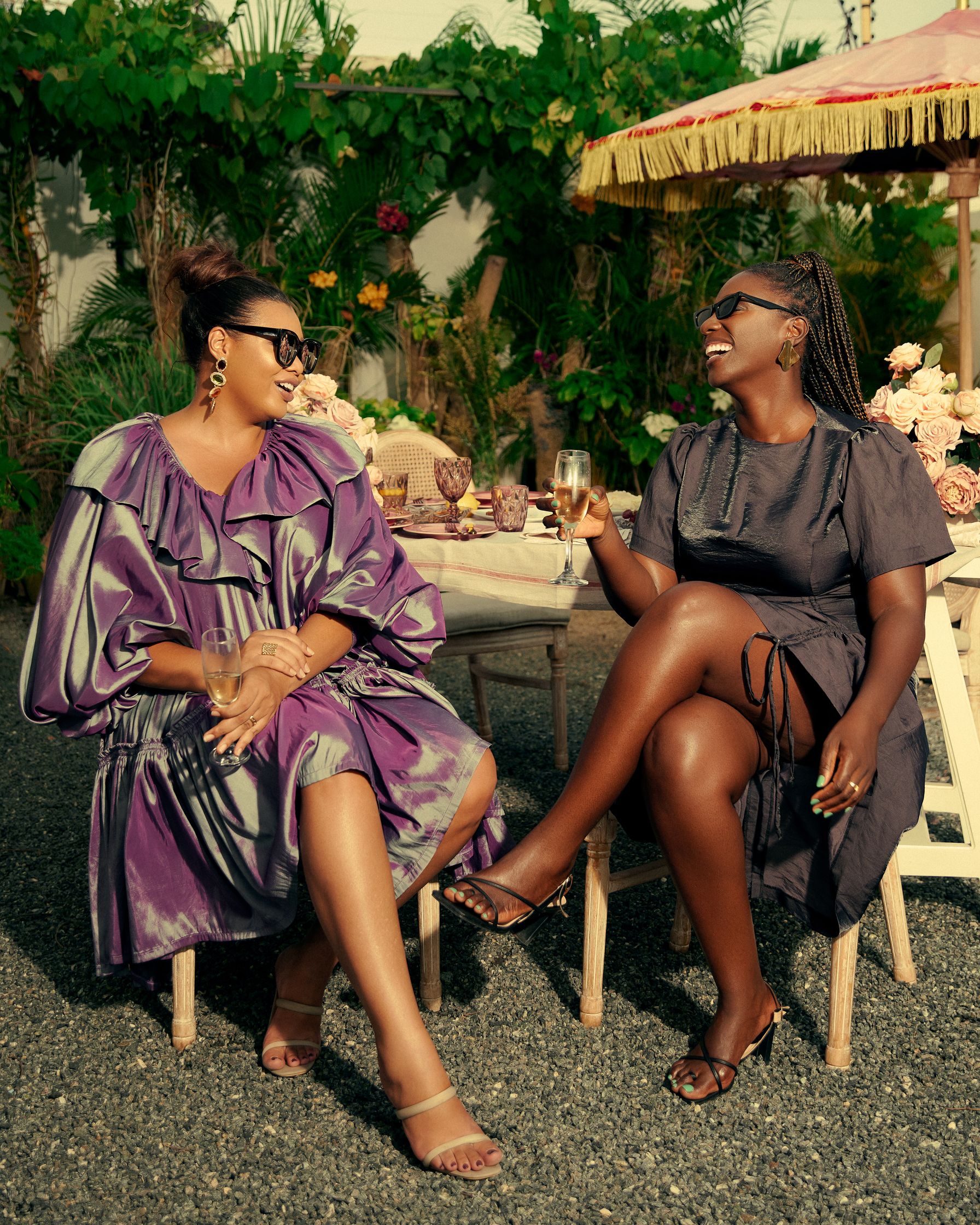 fashion editorial portrait of two women in purple dresses sitting at a table