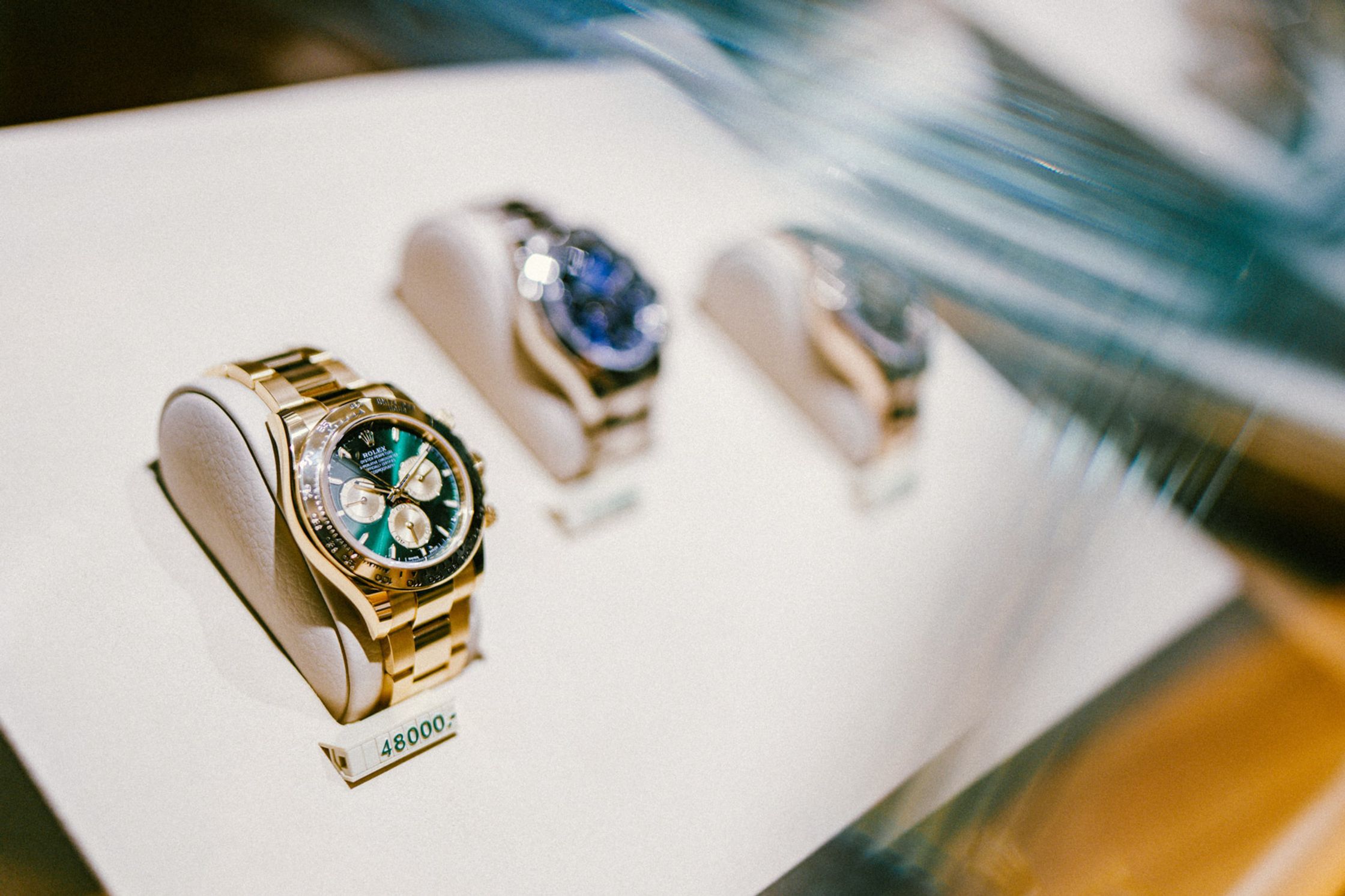 Rolex-Vitrine mit drei Uhren auf weißen Kissen – im Vordergrund goldene Rolex Daytona mit grünem Zifferblatt für 48.000 €, dahinter weitere Rolex-Modelle