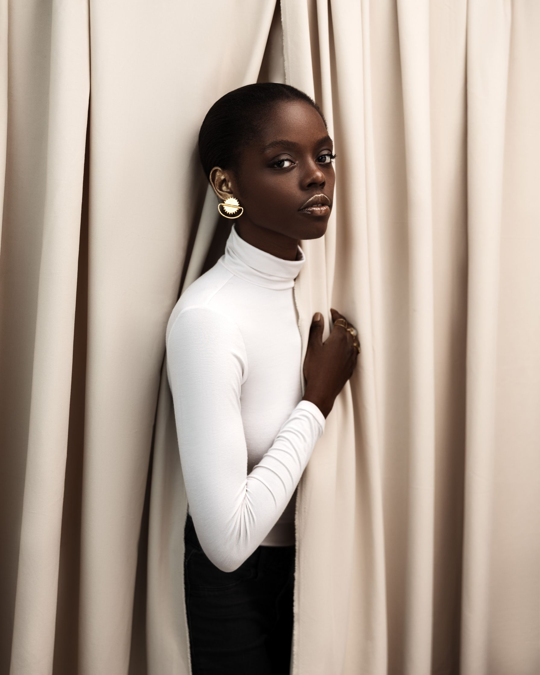 a black woman leaning against a curtain
