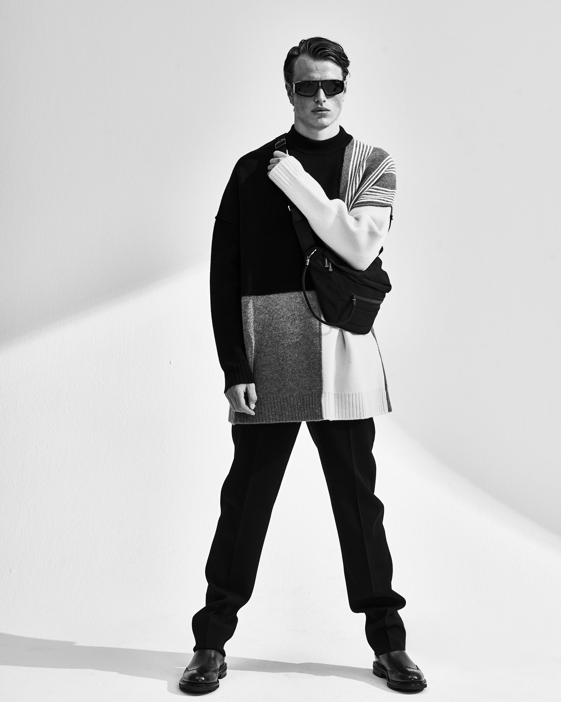 a black and white photo of a man posing with a bag