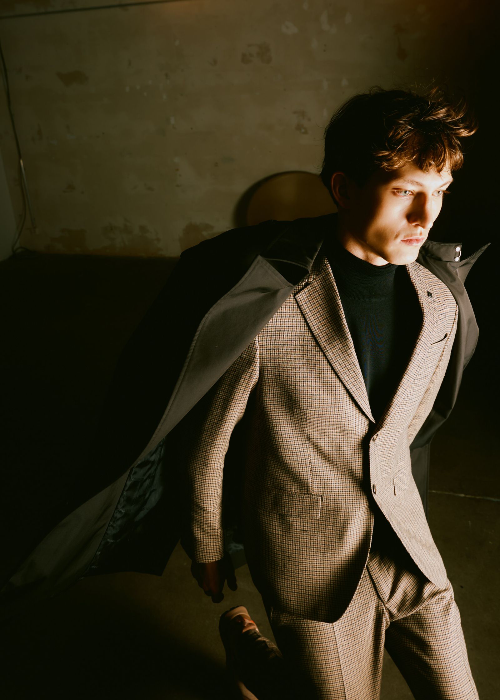 a man in a suit walking in a dark room