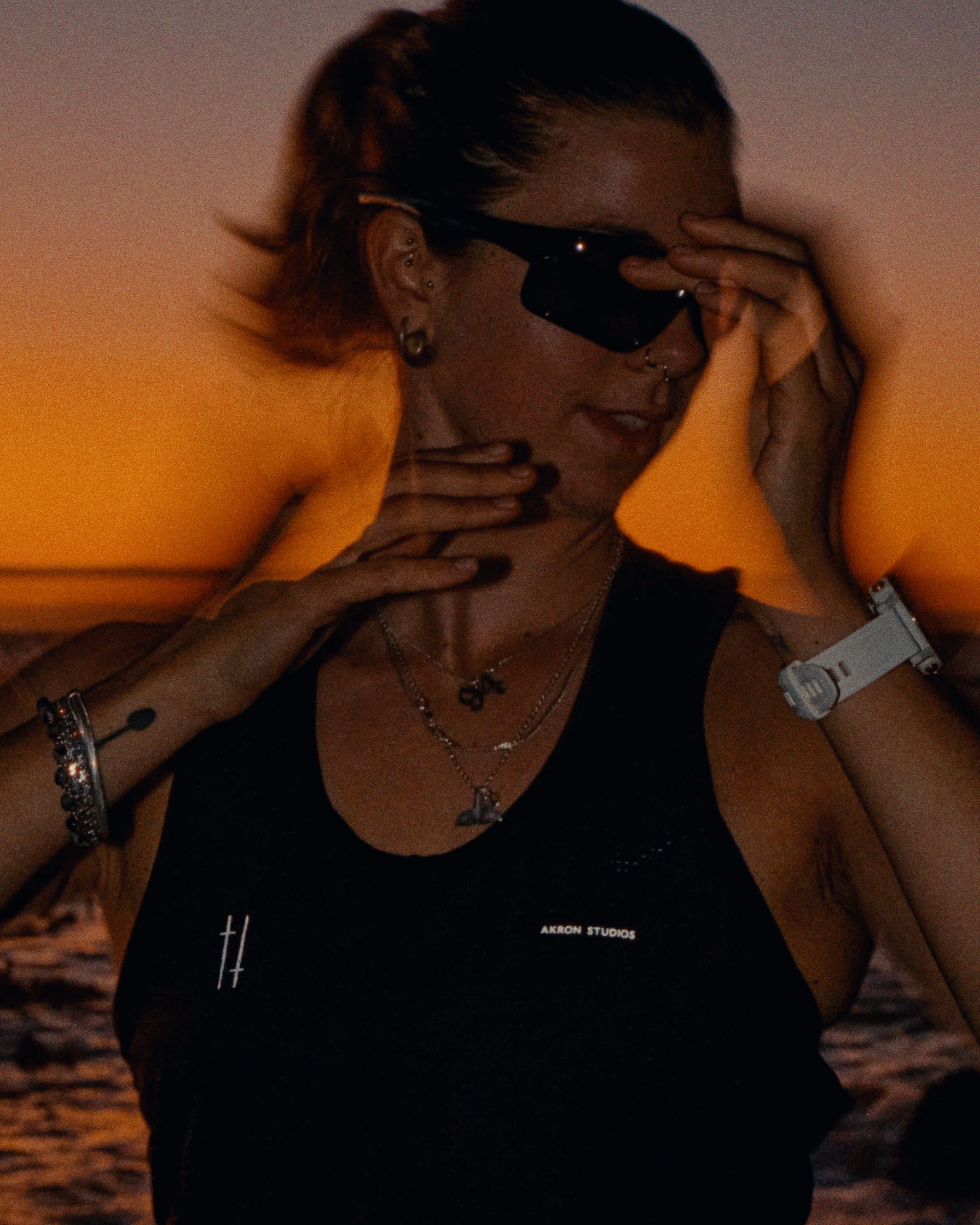 a woman wearing sunglasses in front of a sunset