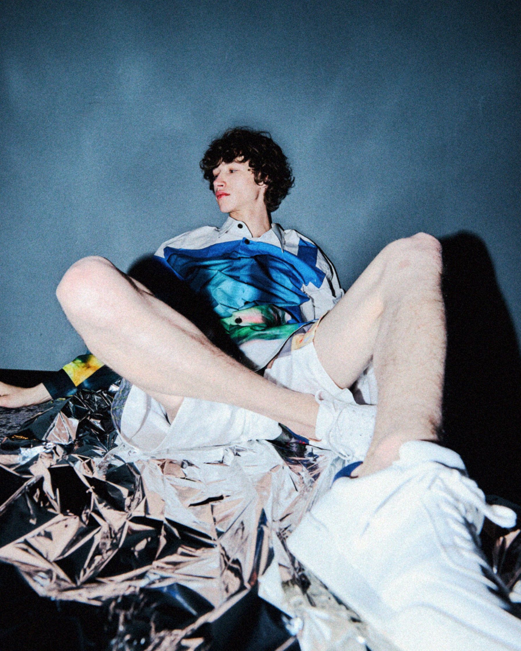 a young man laying on a sheet of foil for GQ by Martin Kula