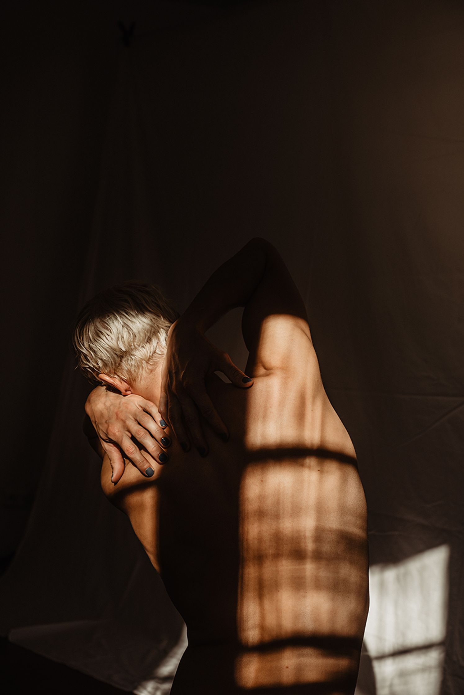 a naked man posing in front of a window