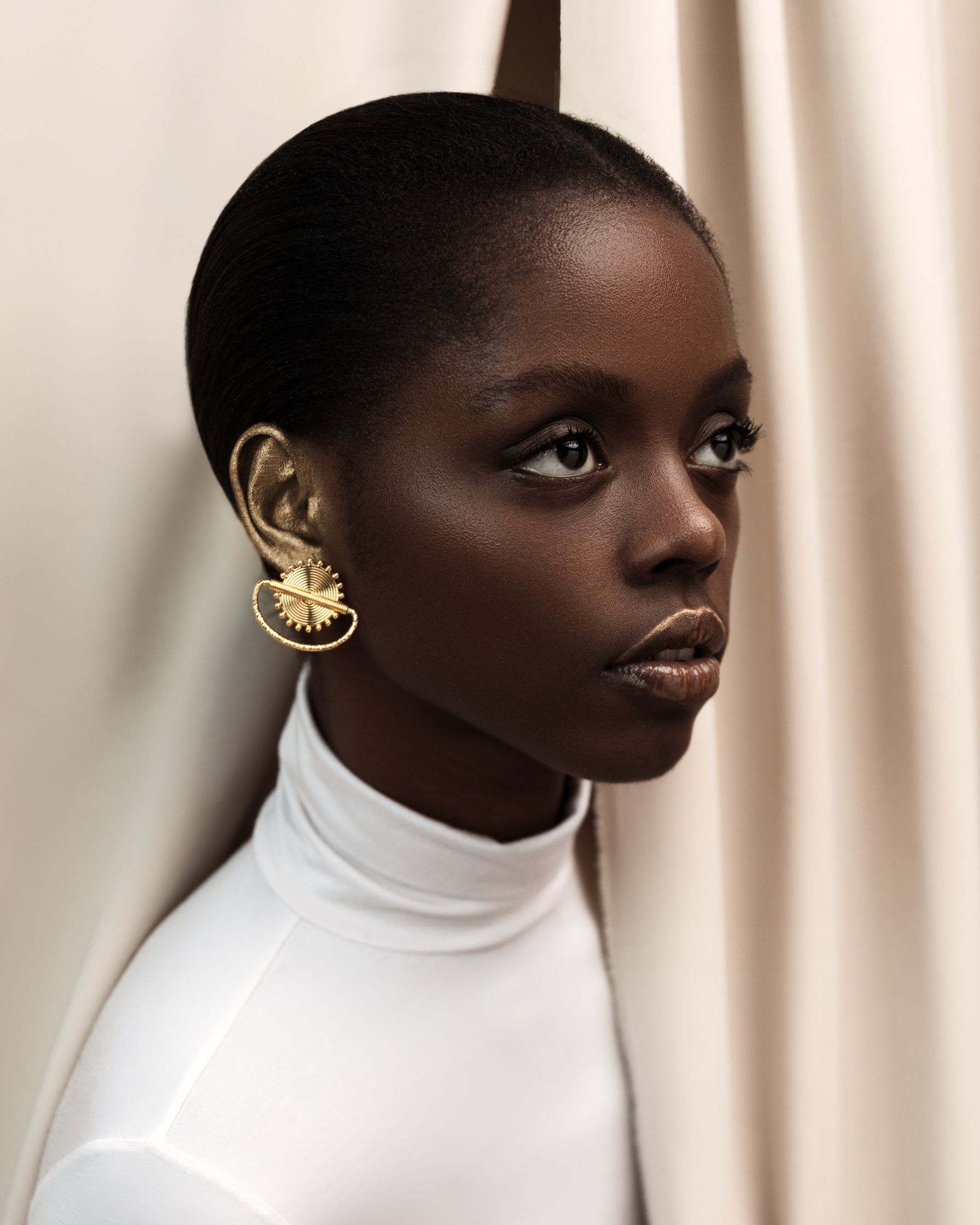 a black woman in a white top and gold earrings