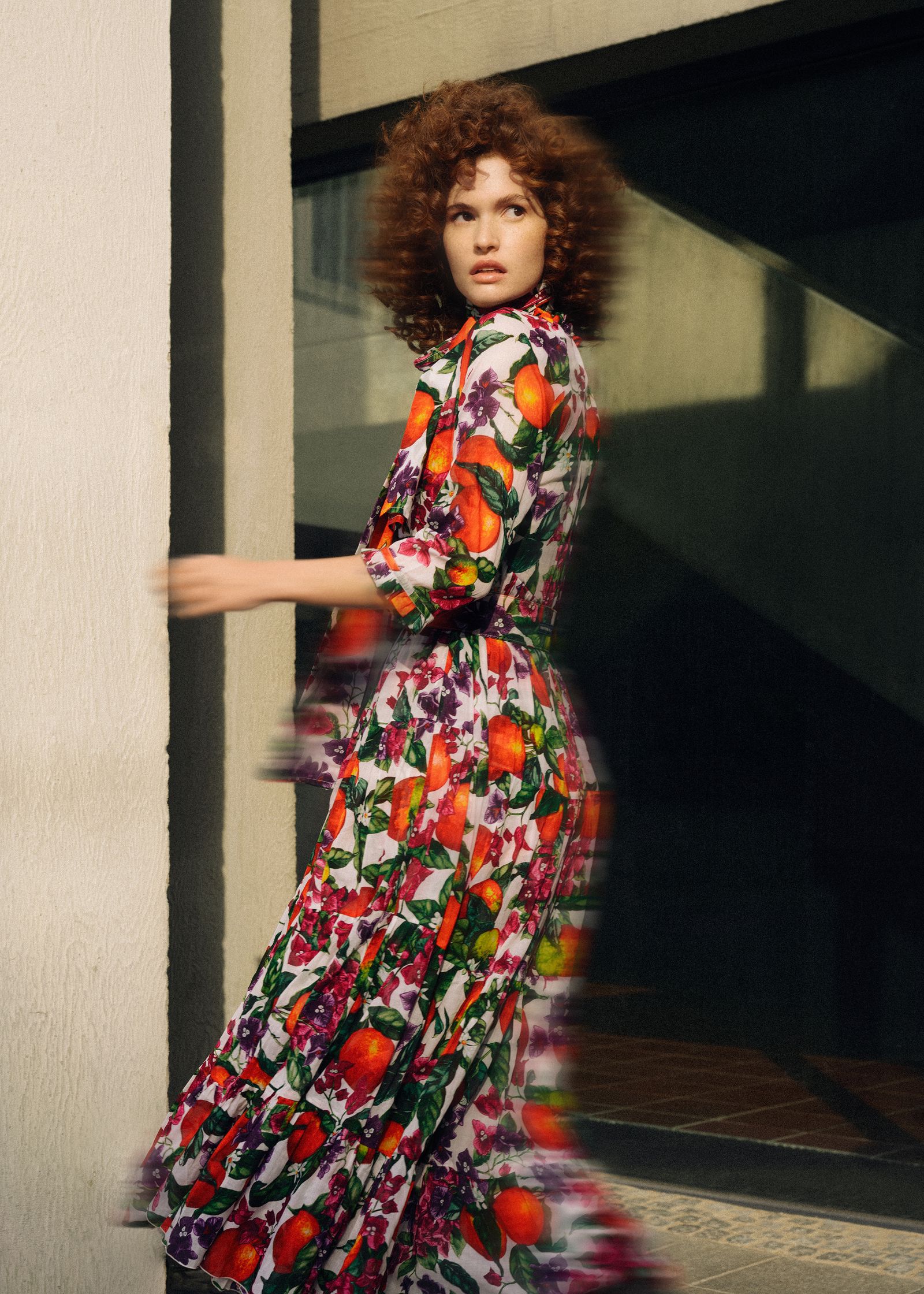 a woman in a colorful floral dress is walking down the street