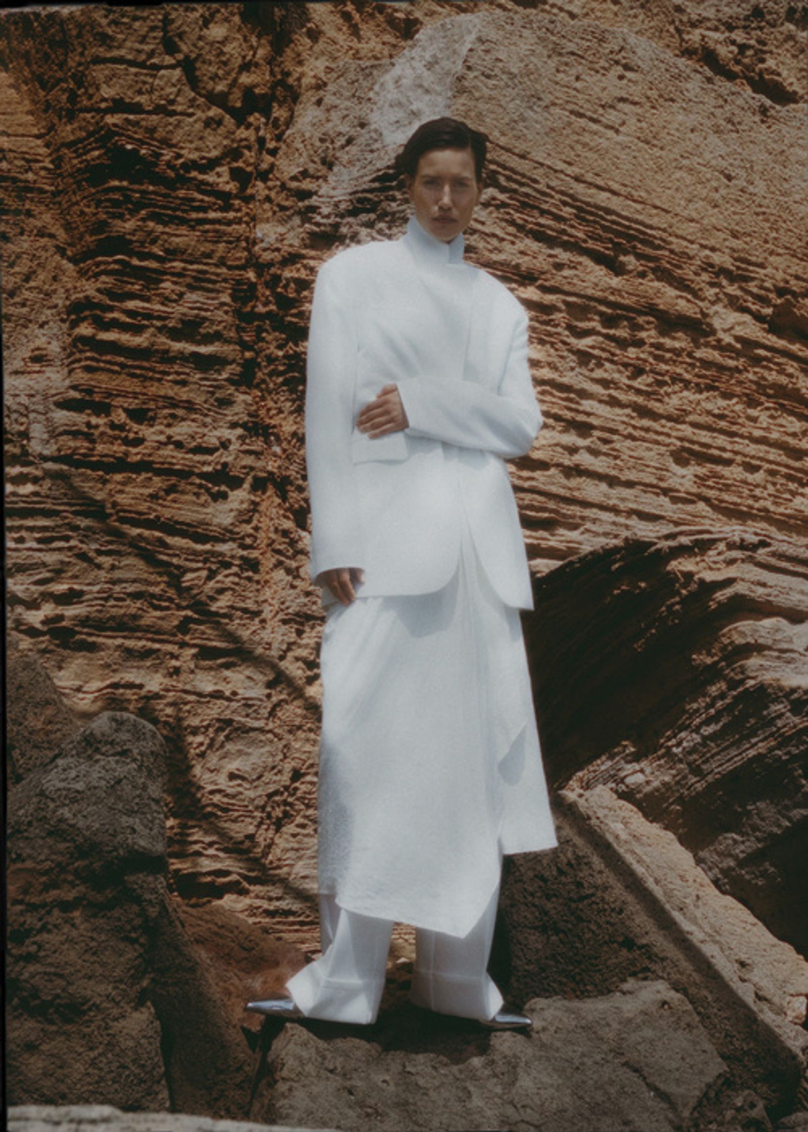 a man in a white suit standing on a rock