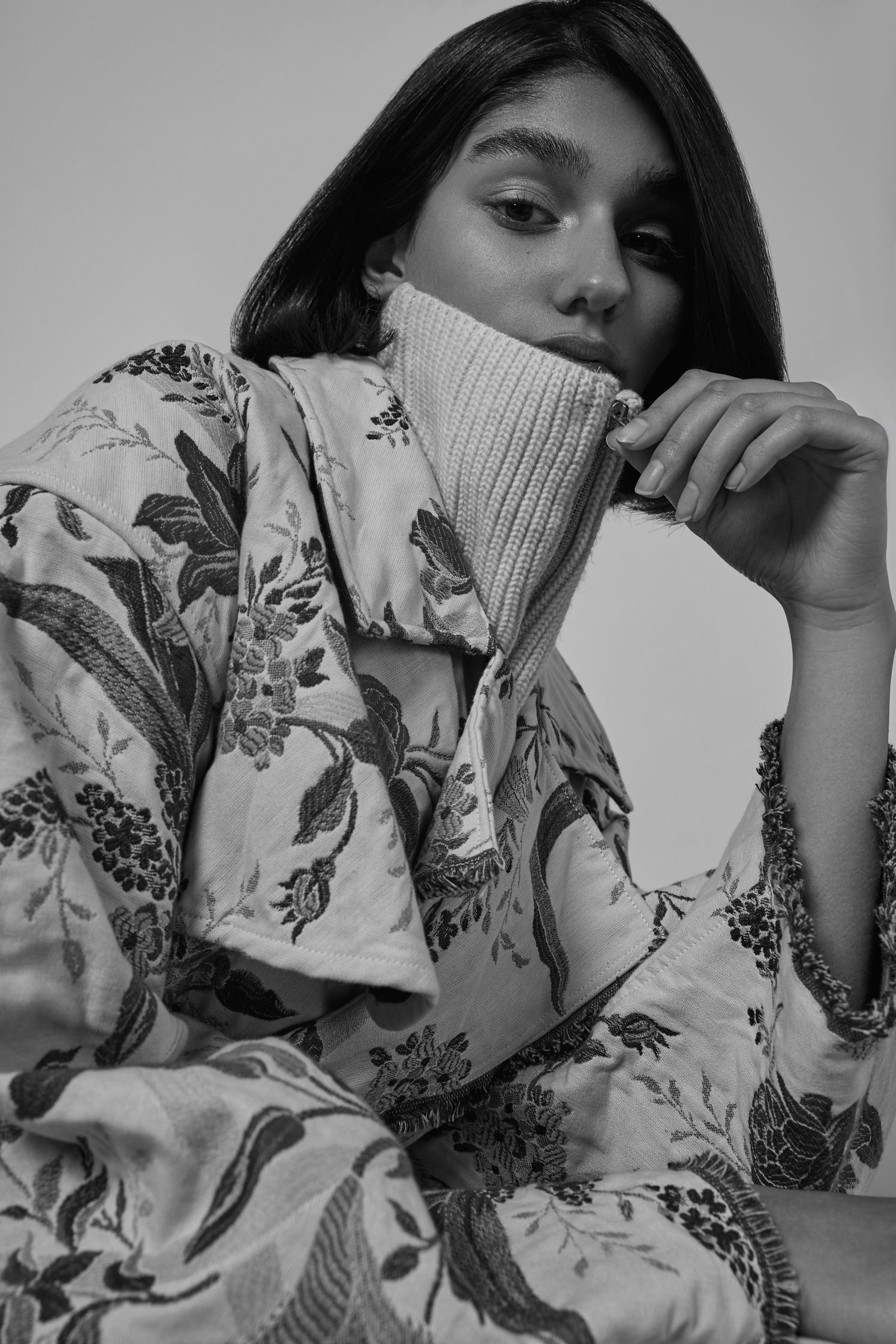 a black and white photo of a woman wearing a floral coat