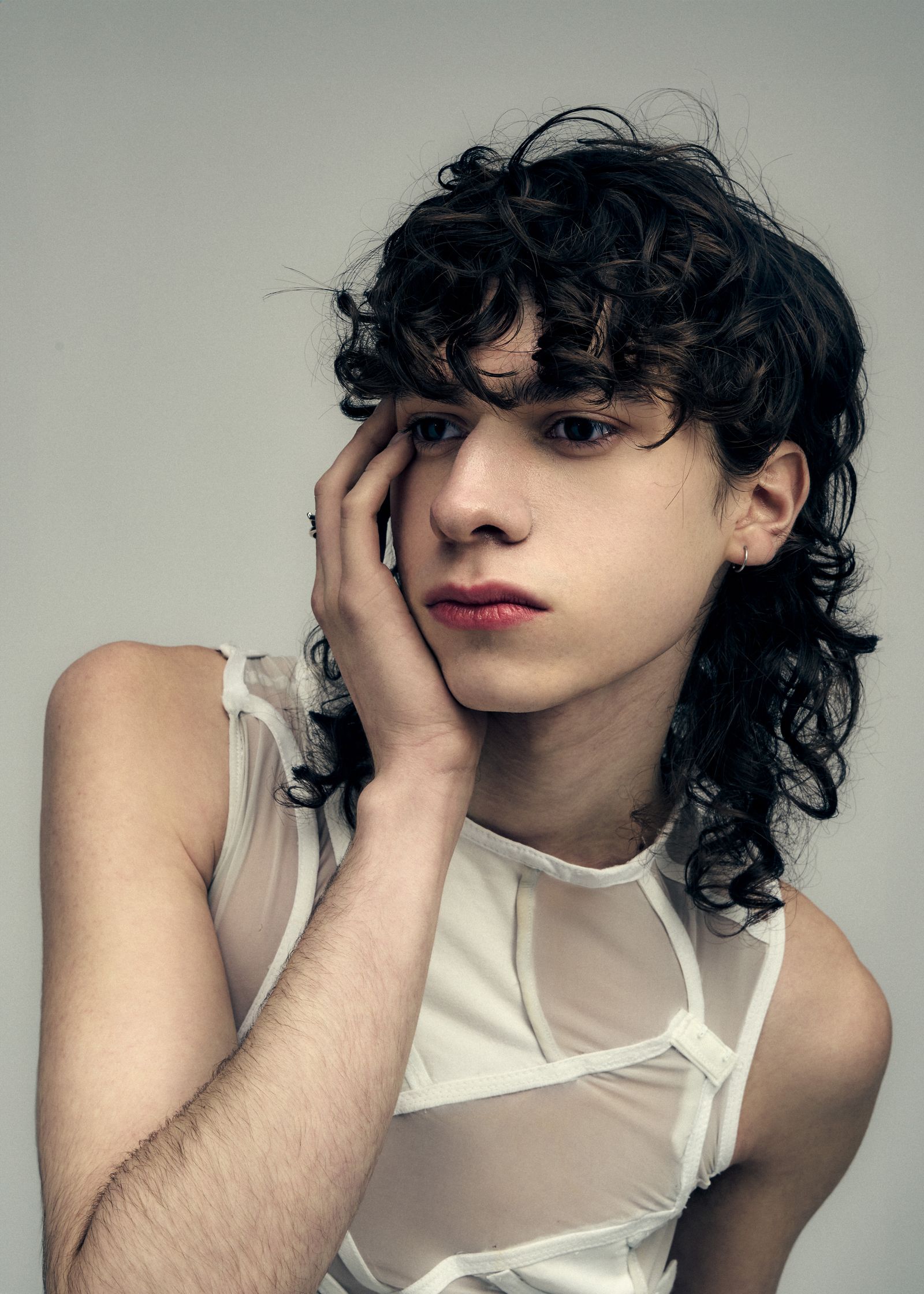 a young man with curly hair posing for a photo