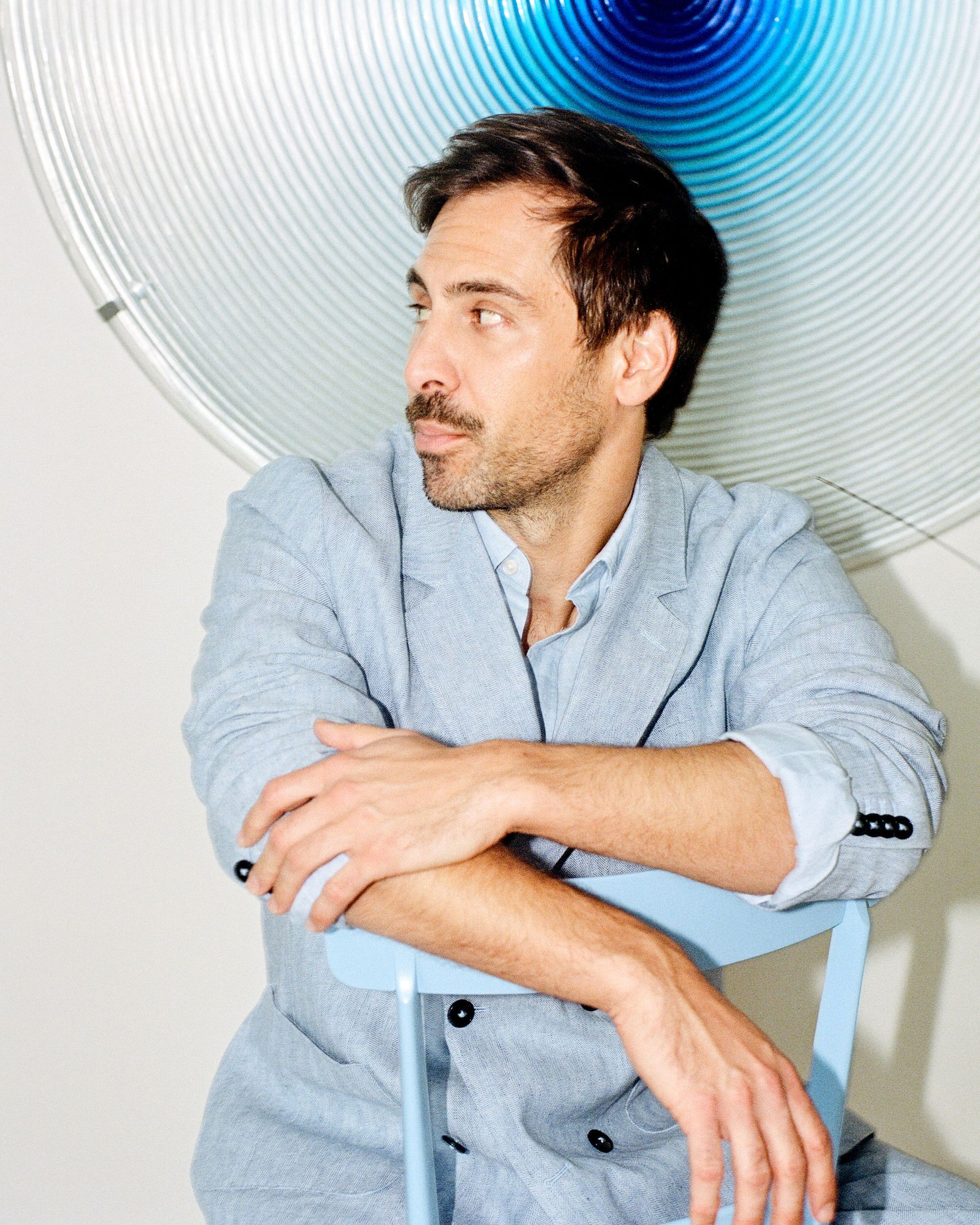 Max Giesinger sitting on a chair in front of a blue light