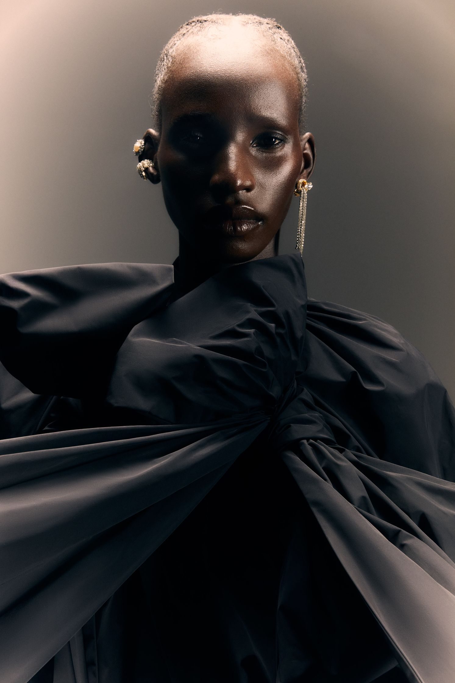 a black woman in a black dress posing in front of a gray background