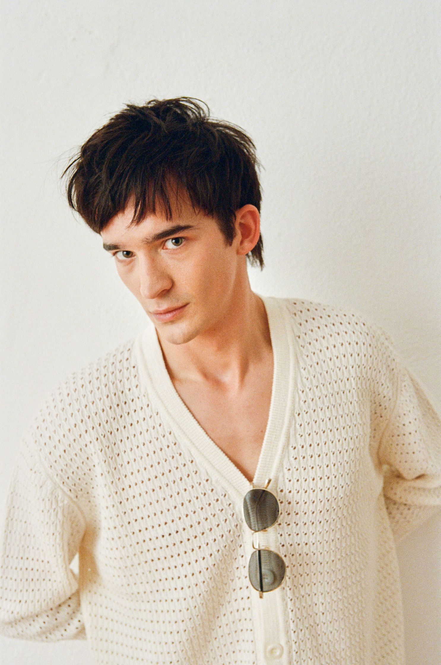 a young man wearing a white sweater and sunglasses