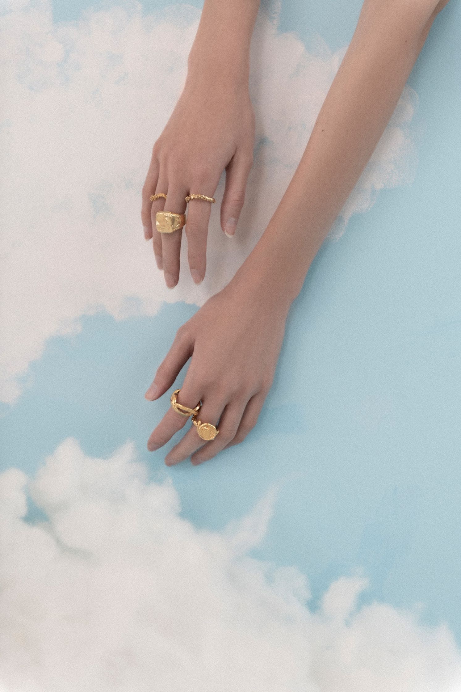 a woman wearing a gold ring on top of a cloud
