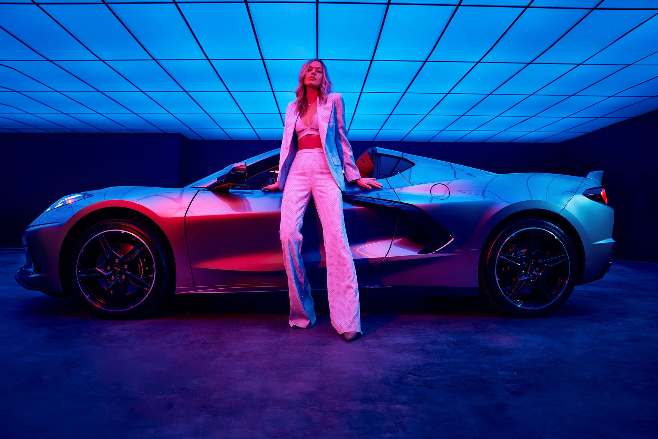 a woman posing in front of a sports car