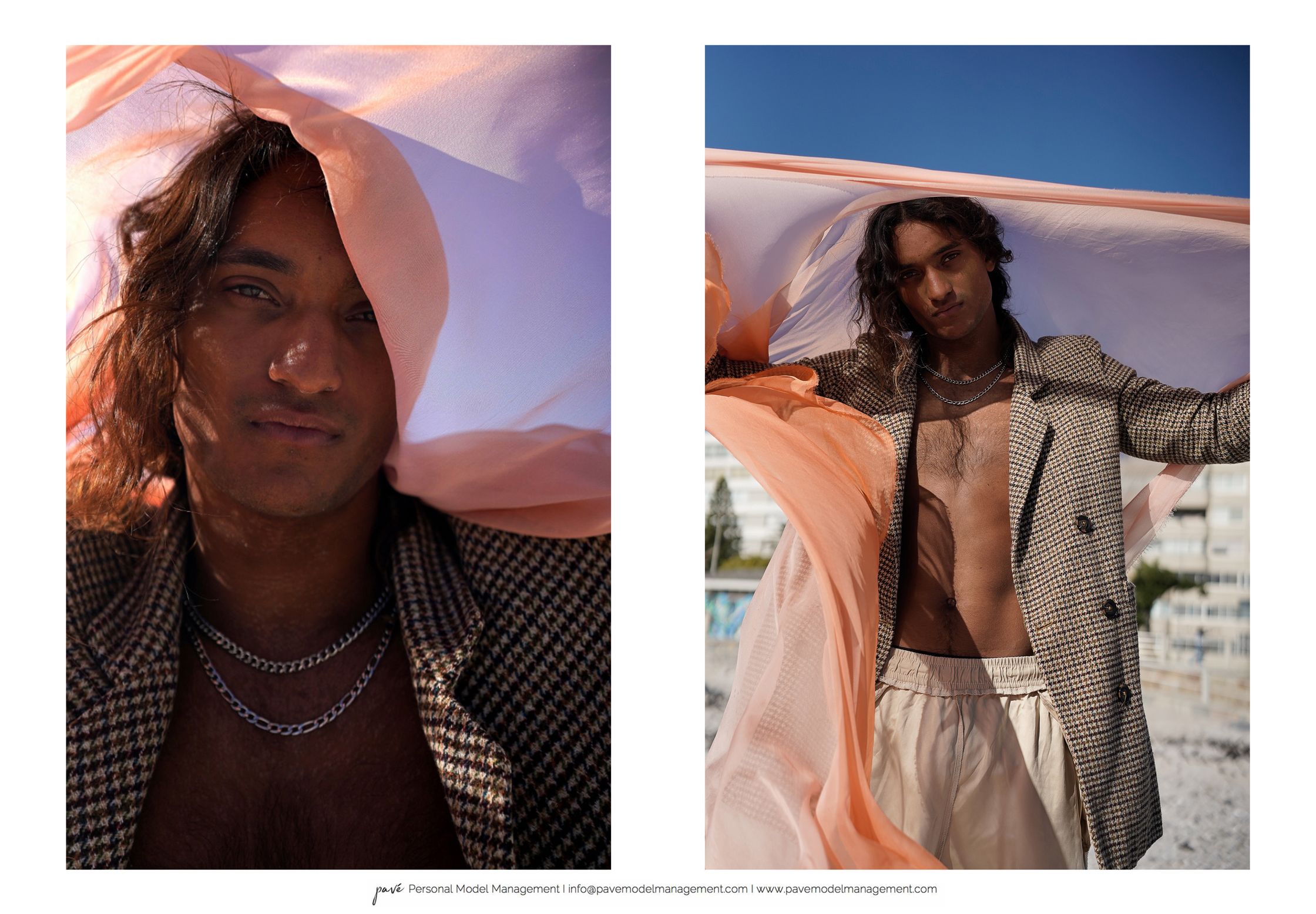 A man with long dark hair, wearing a plaid blazer and silver necklaces, looks directly at the camera with a peach-colored fabric draped around him.