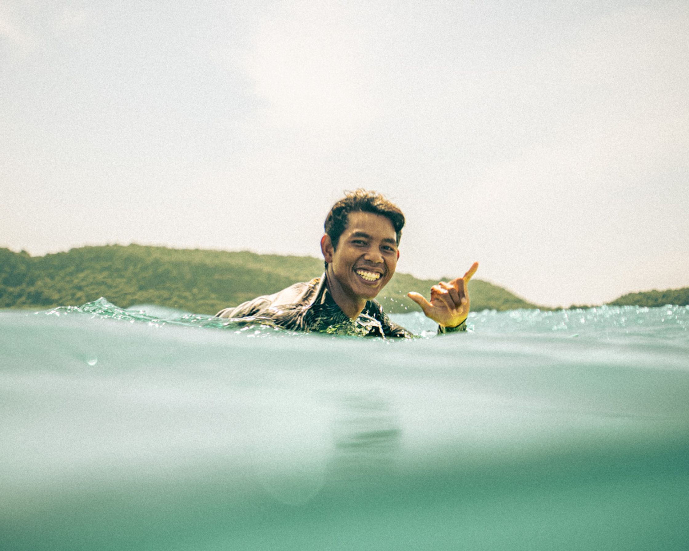 An happy surfer  giving a shaka sign to the camera at Gerupuk.