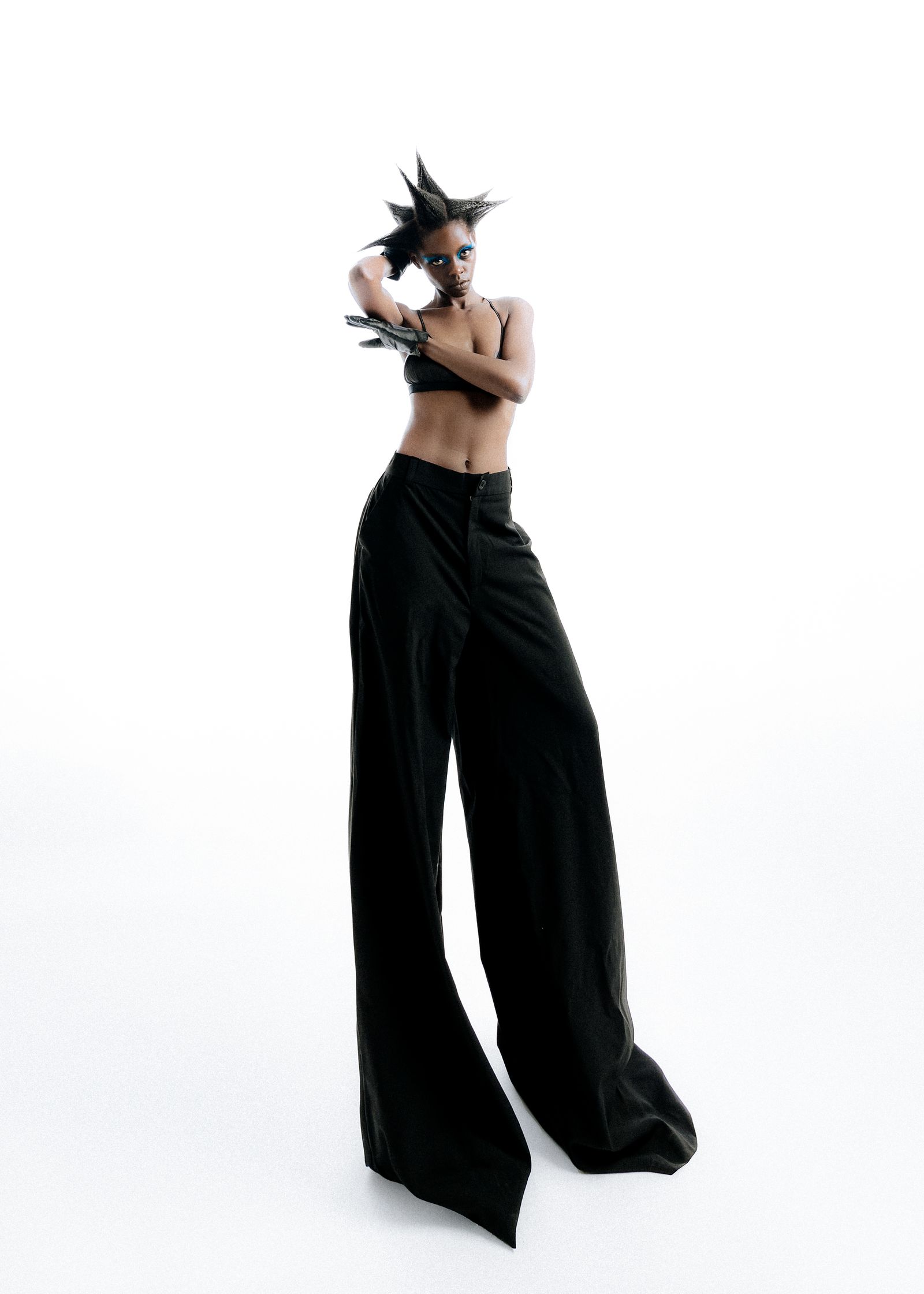 a fashion portrait of woman in black pants is posing on a white background
