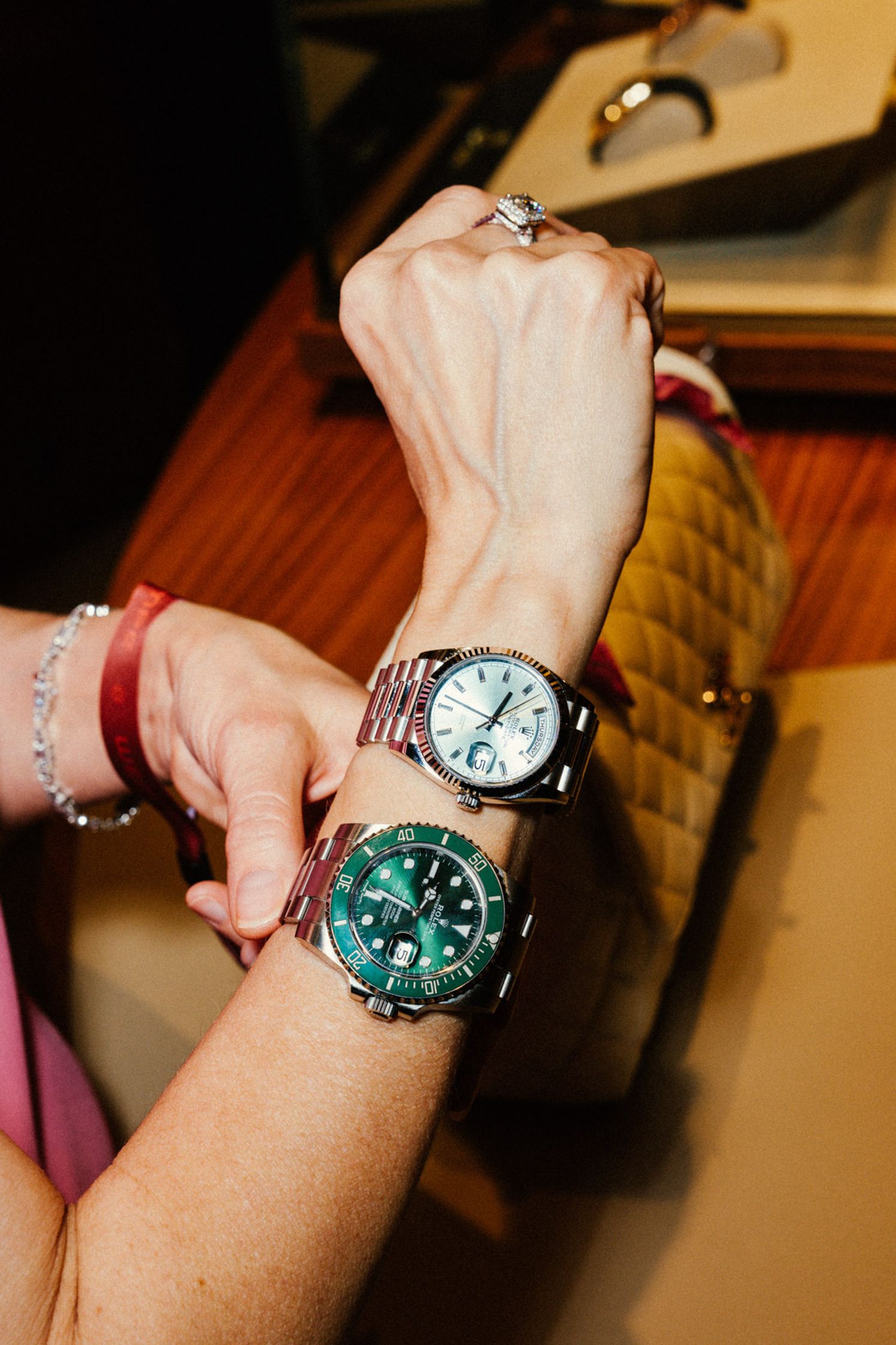 Detail-Aufnahme: Rolex-Beraterin legt einem Kunden eine grüne Rolex Submariner ans Handgelenk, Uhren-Tablett im Hintergrund, intimer Anproben-Moment Rolex Boutique Berlin