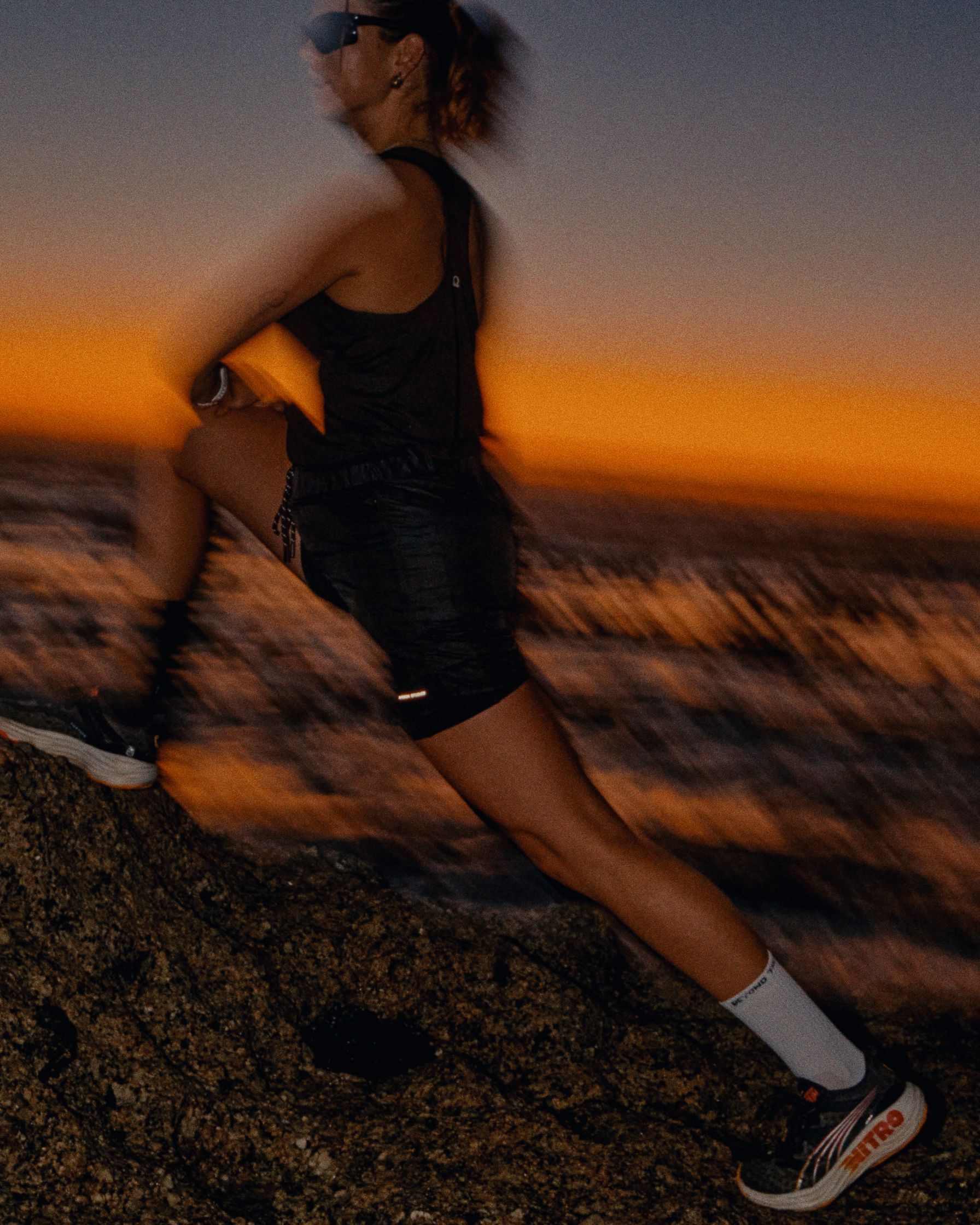 a woman running on a rock at sunset