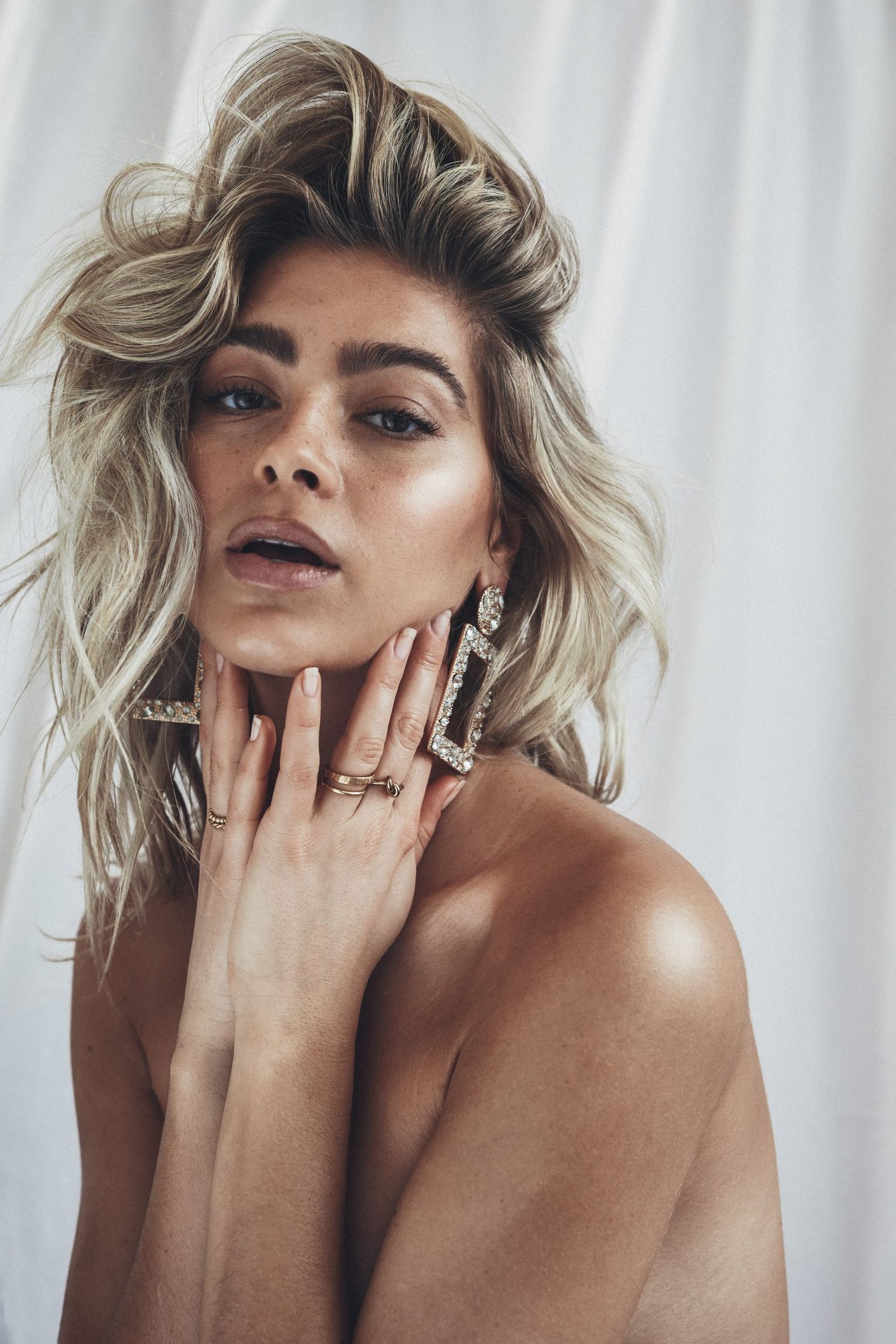 a woman in a nude outfit posing with her hands on her face