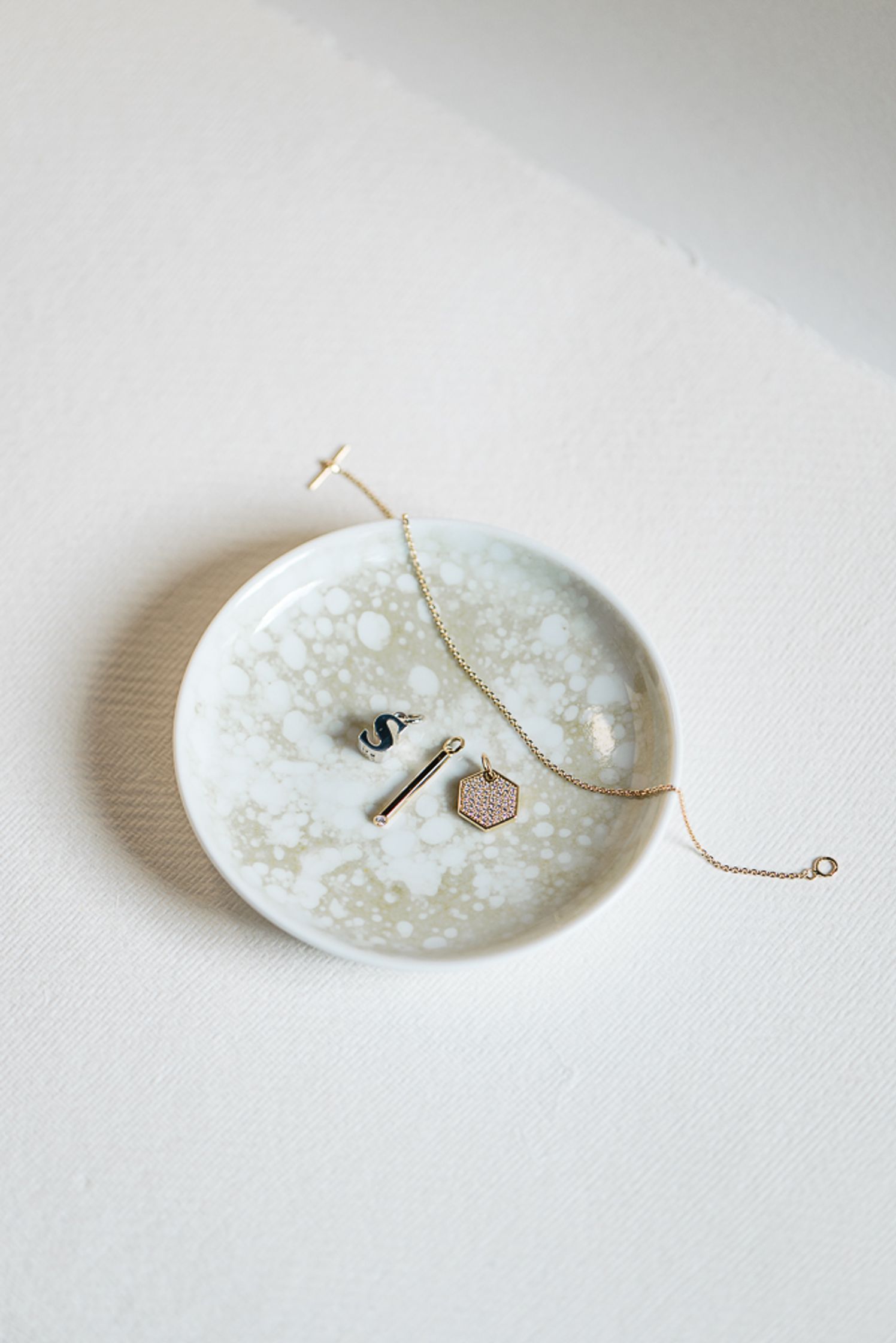 a white plate with a gold ring on it by maren jewellery