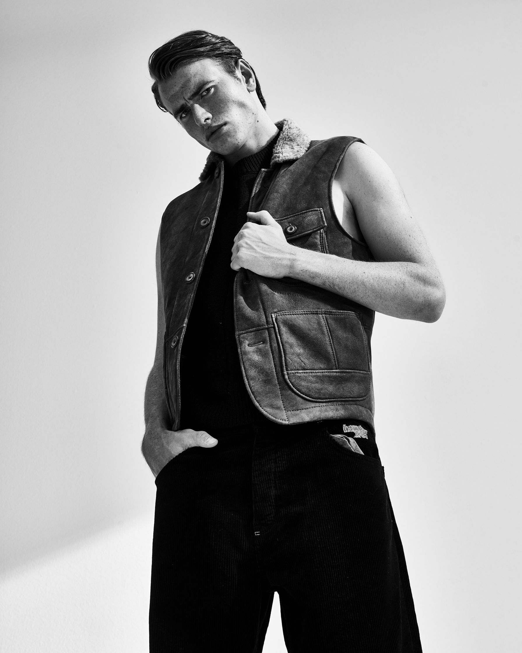 a black and white photo of a man in a leather vest