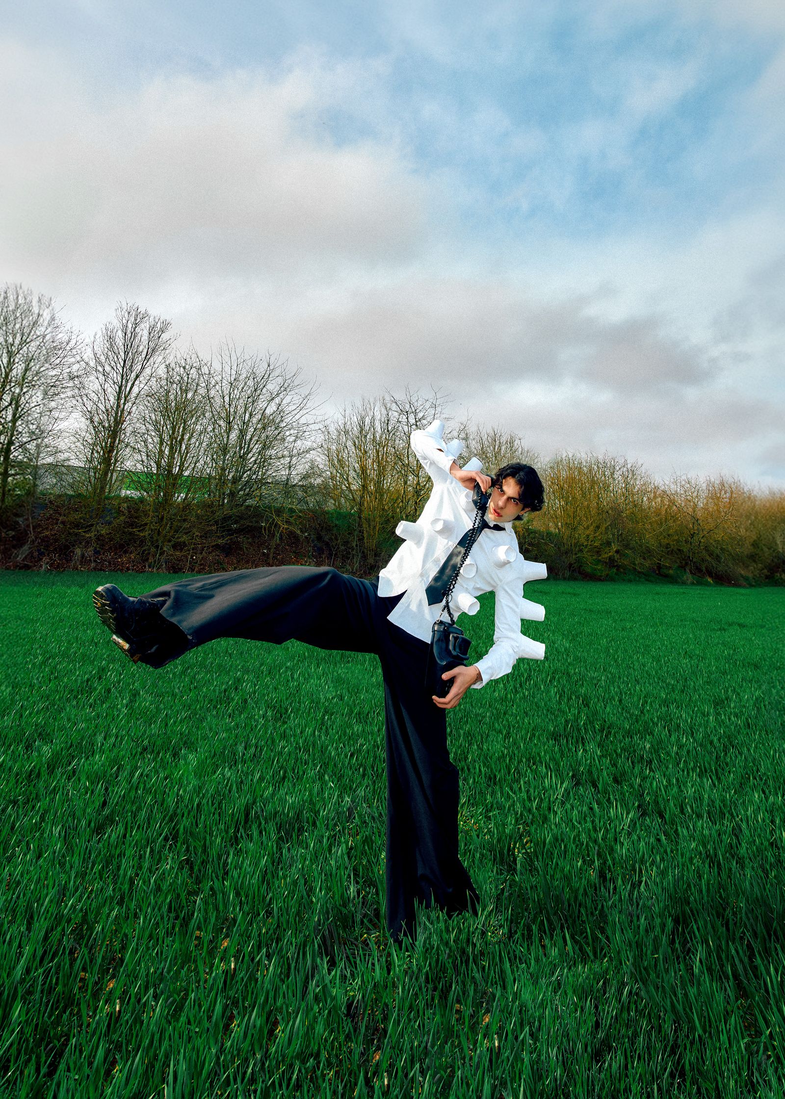 a man in a white shirt is kicking his leg in a grassy field