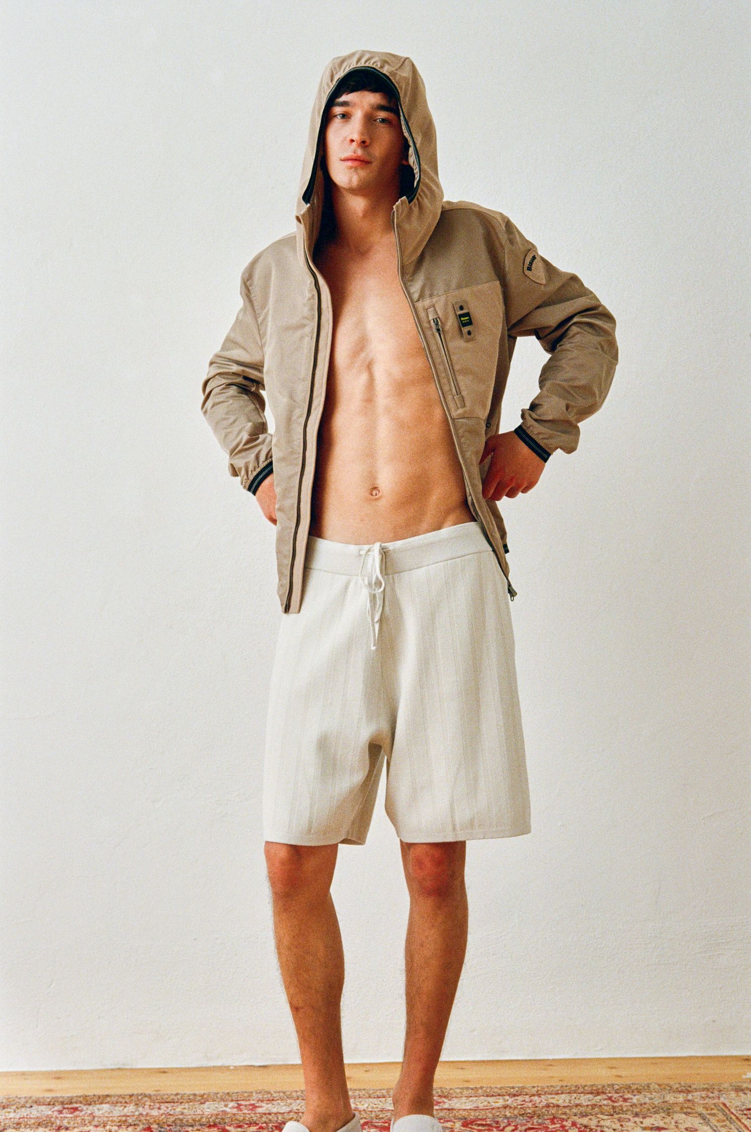 a man in shorts and a hoodie standing on a rug