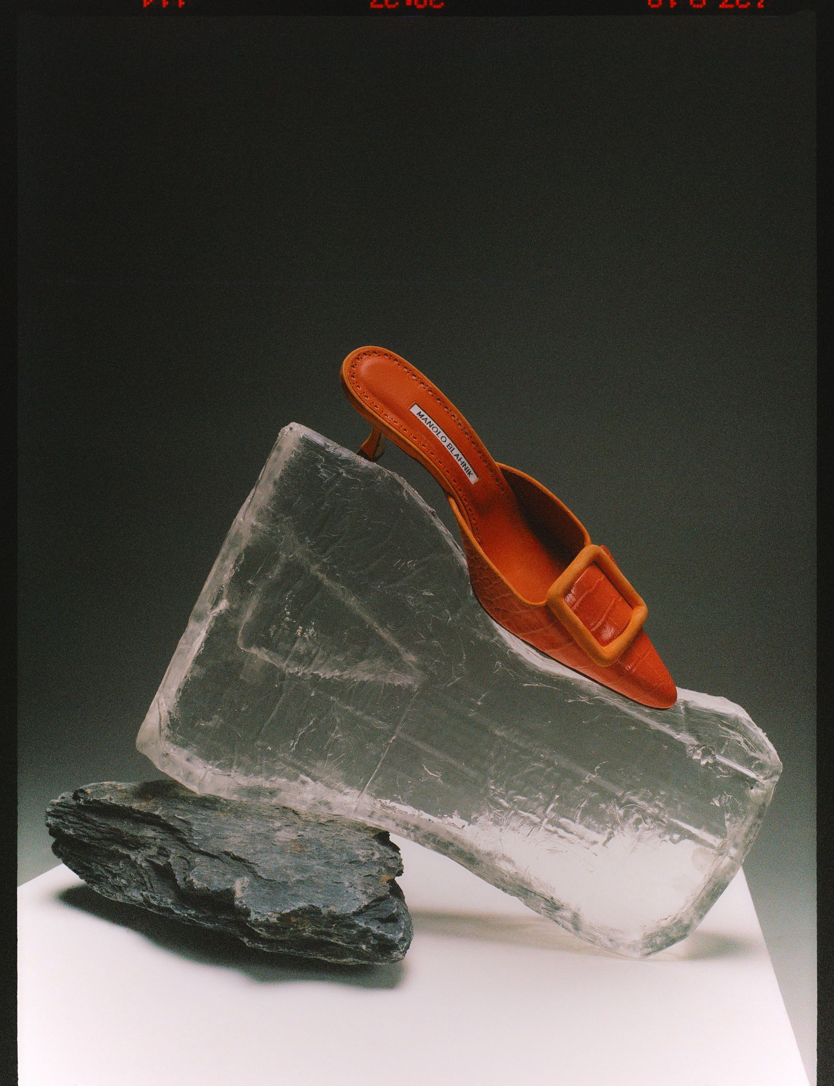 a sculpture of an orange shoe on top of a rock