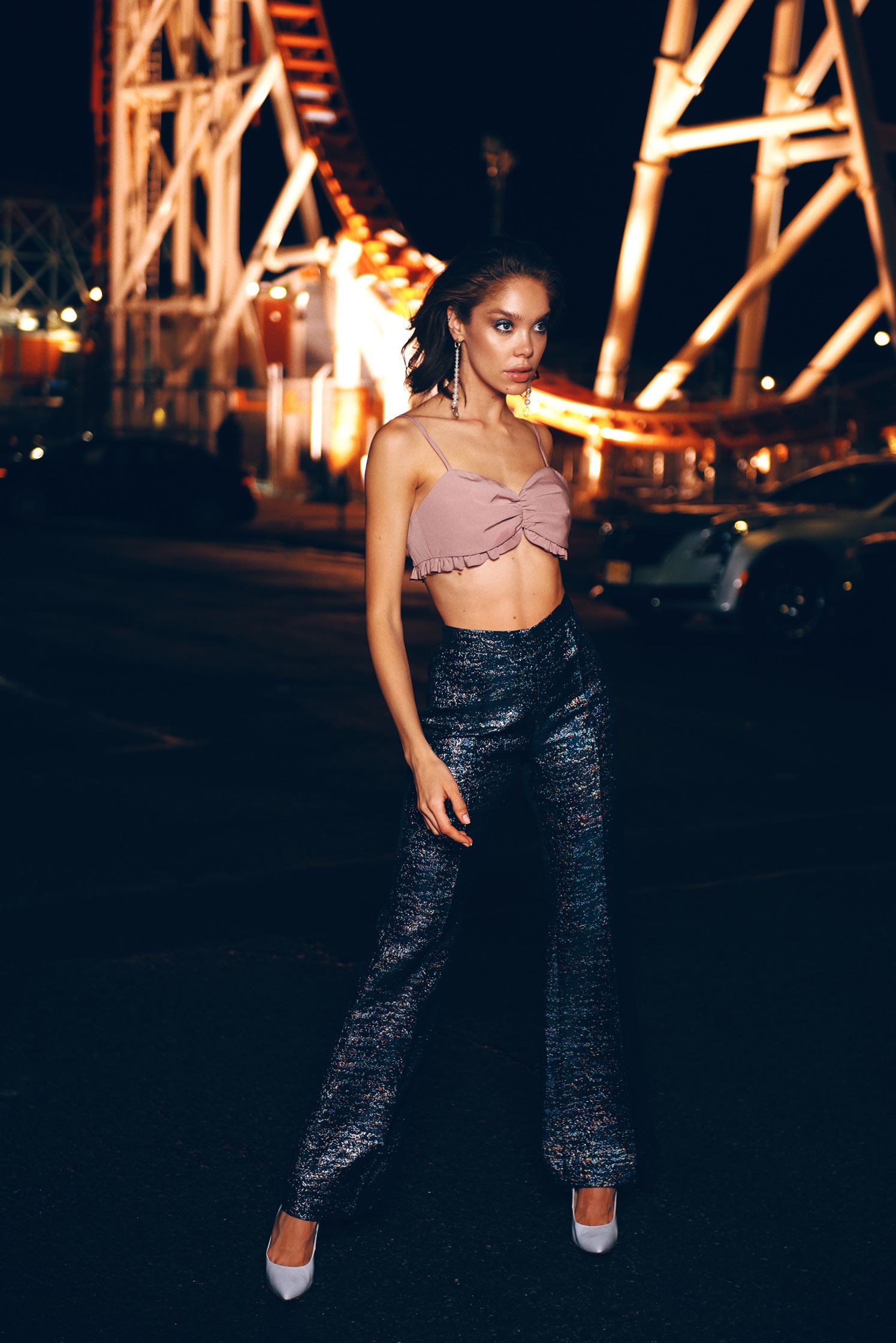 a woman standing in front of a ferris wheel at night