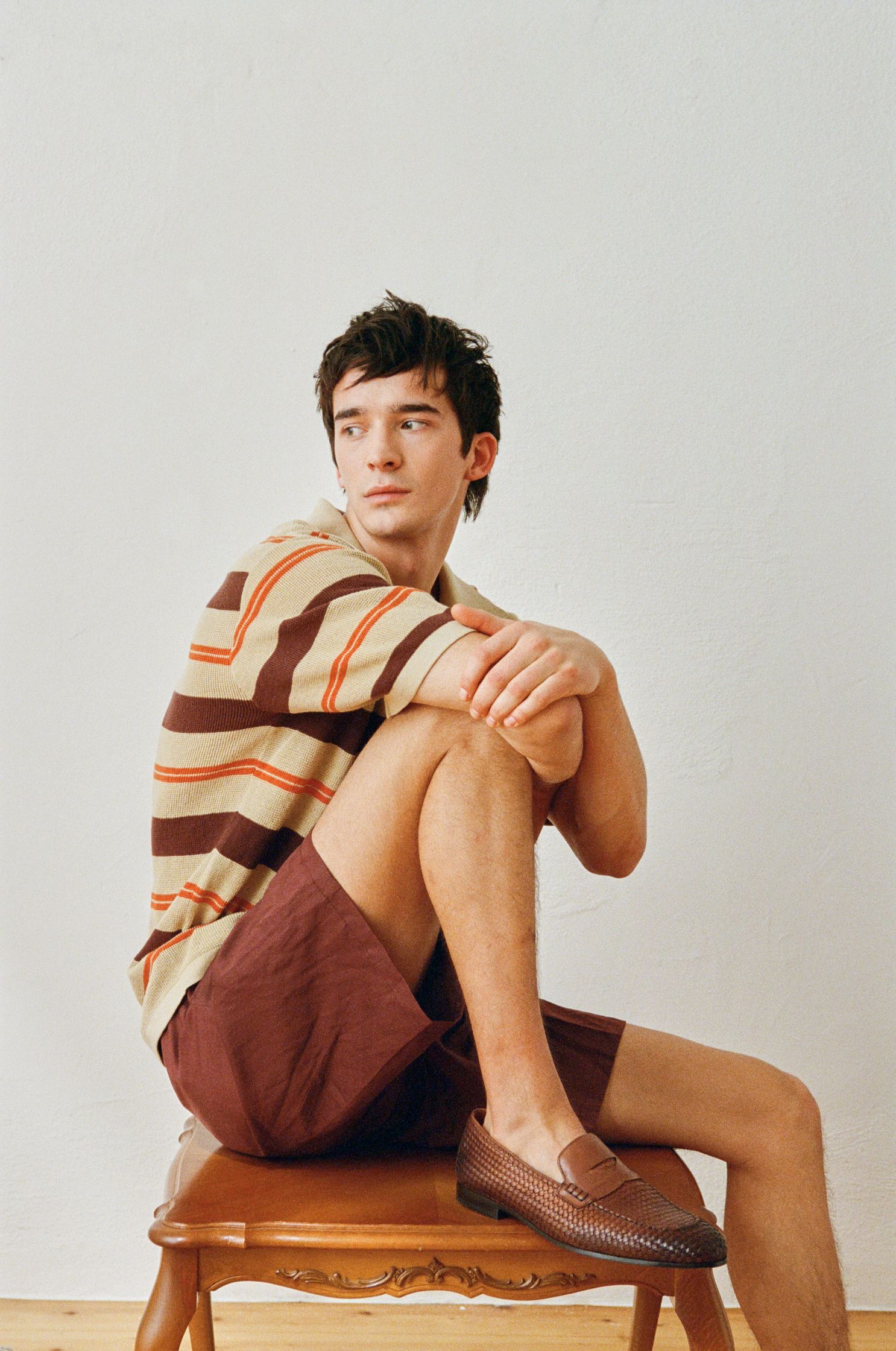 a man sitting on a chair wearing a striped shirt and shorts