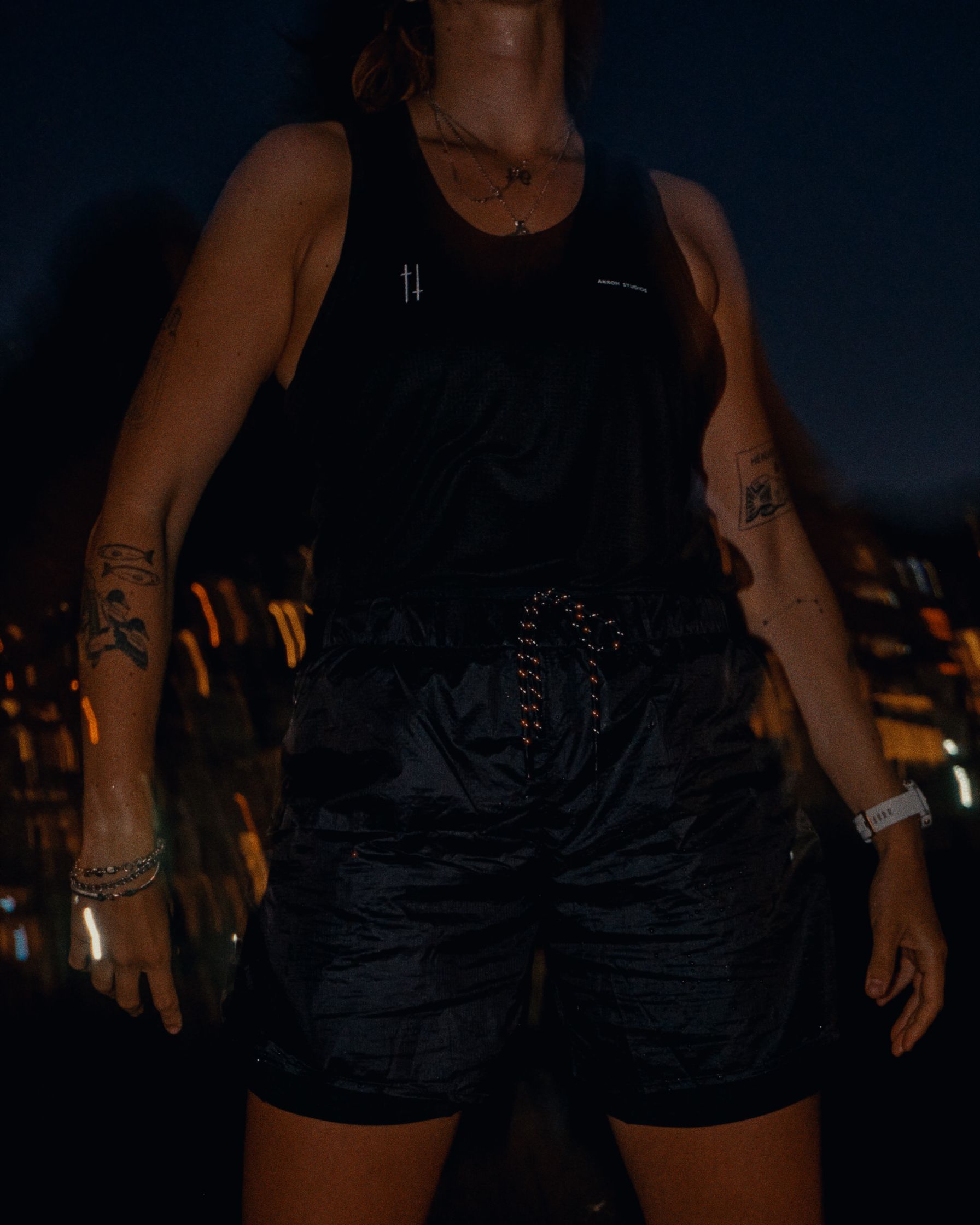 a woman wearing a black tank top and shorts at night
