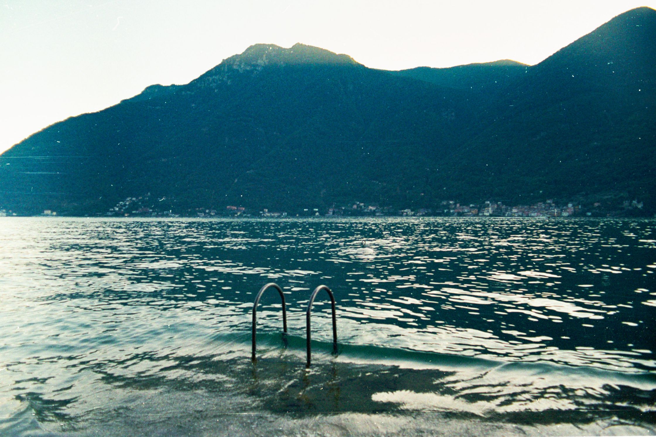 A stair partially submerged by the crystal waters of Lake Como, acting as a silent invitation to step into the landscape and surrender to the lake.