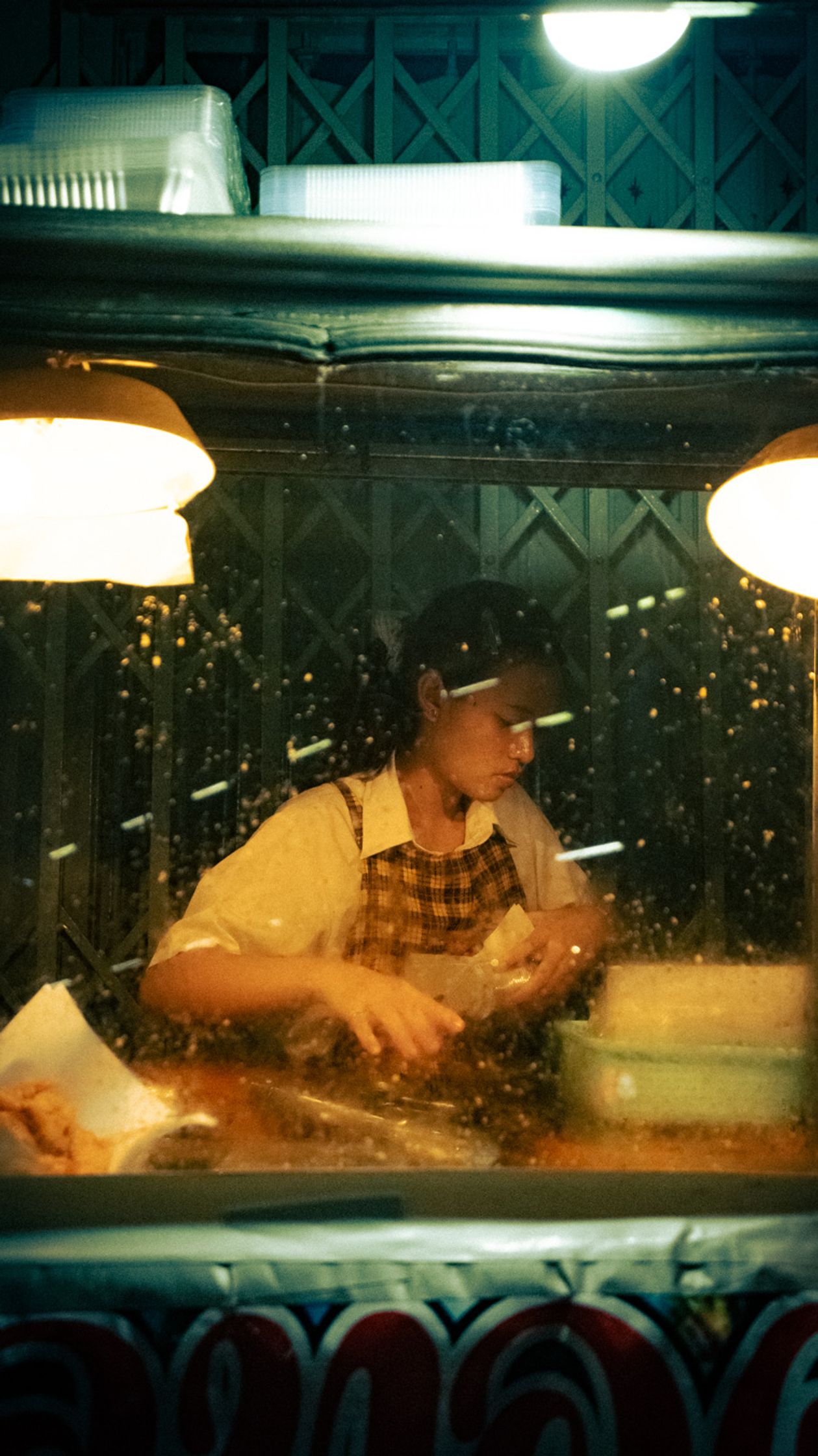 Authentic documentary shot of a woman cooking at her street food stall in Bangkok during the night.