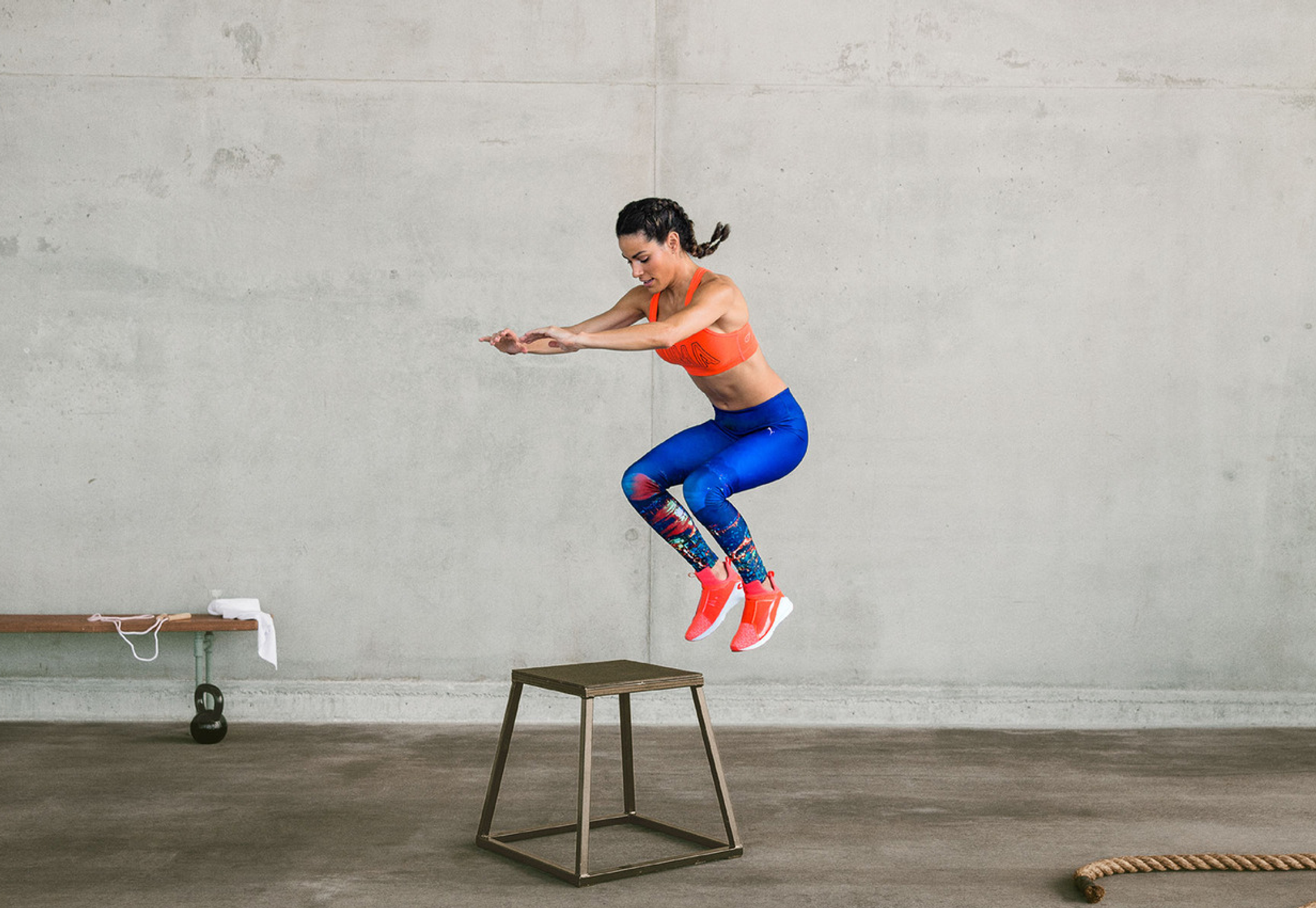 a woman is jumping on a stool in a gym puma