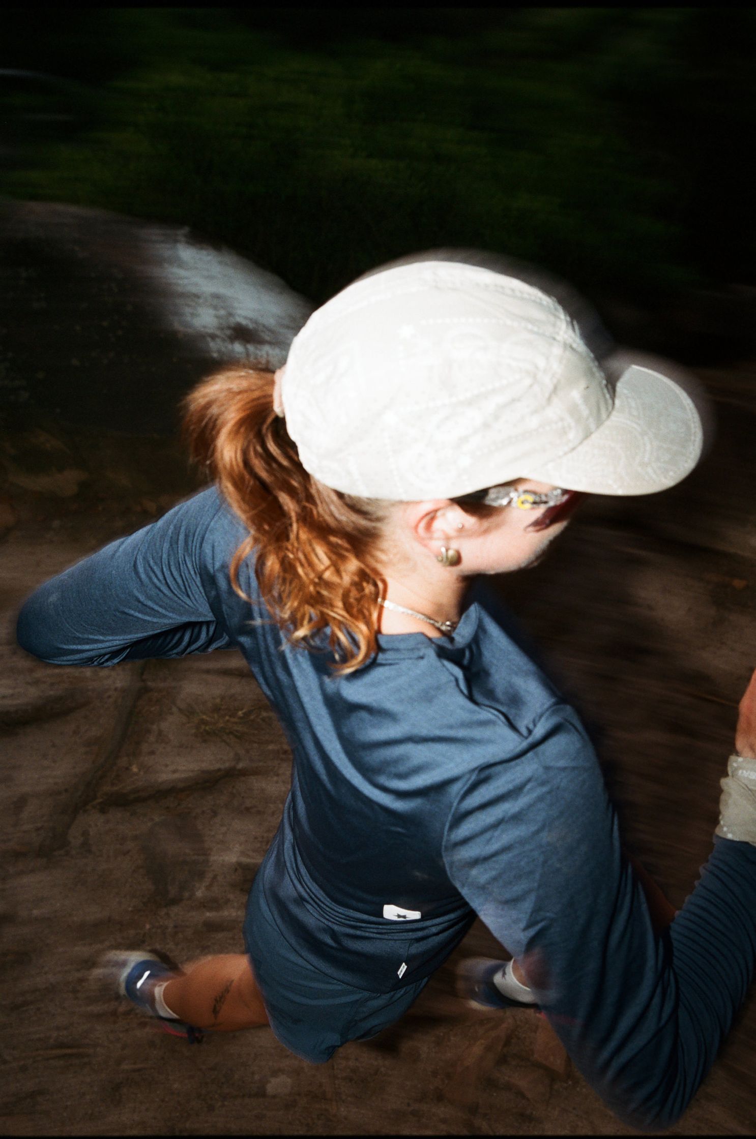a woman wearing a hat and running on a trail