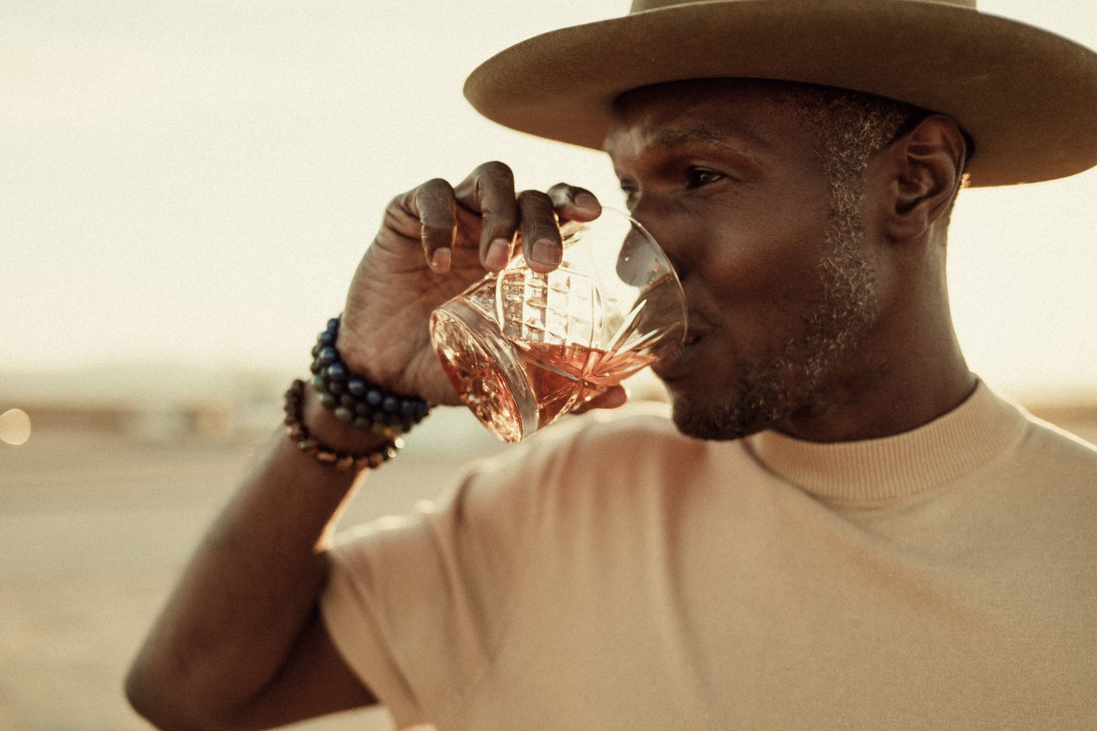 a man in a hat drinking a glass of wiskey
