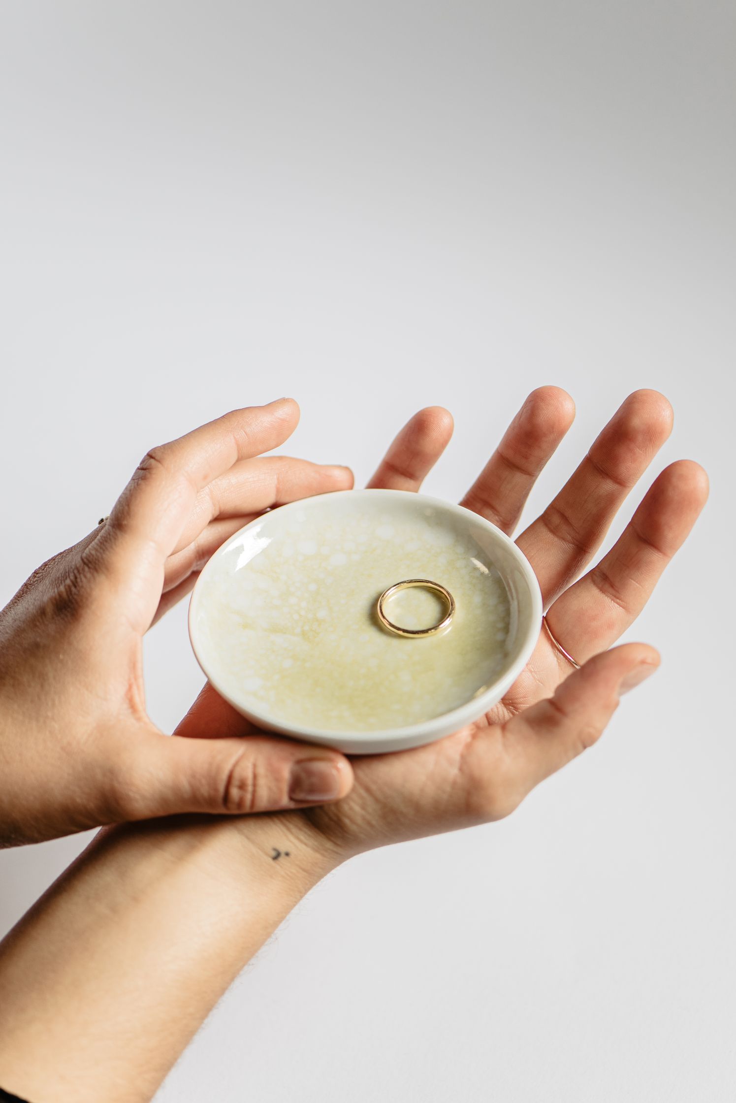 a person holding a small plate with a ring on it by maren jewellery