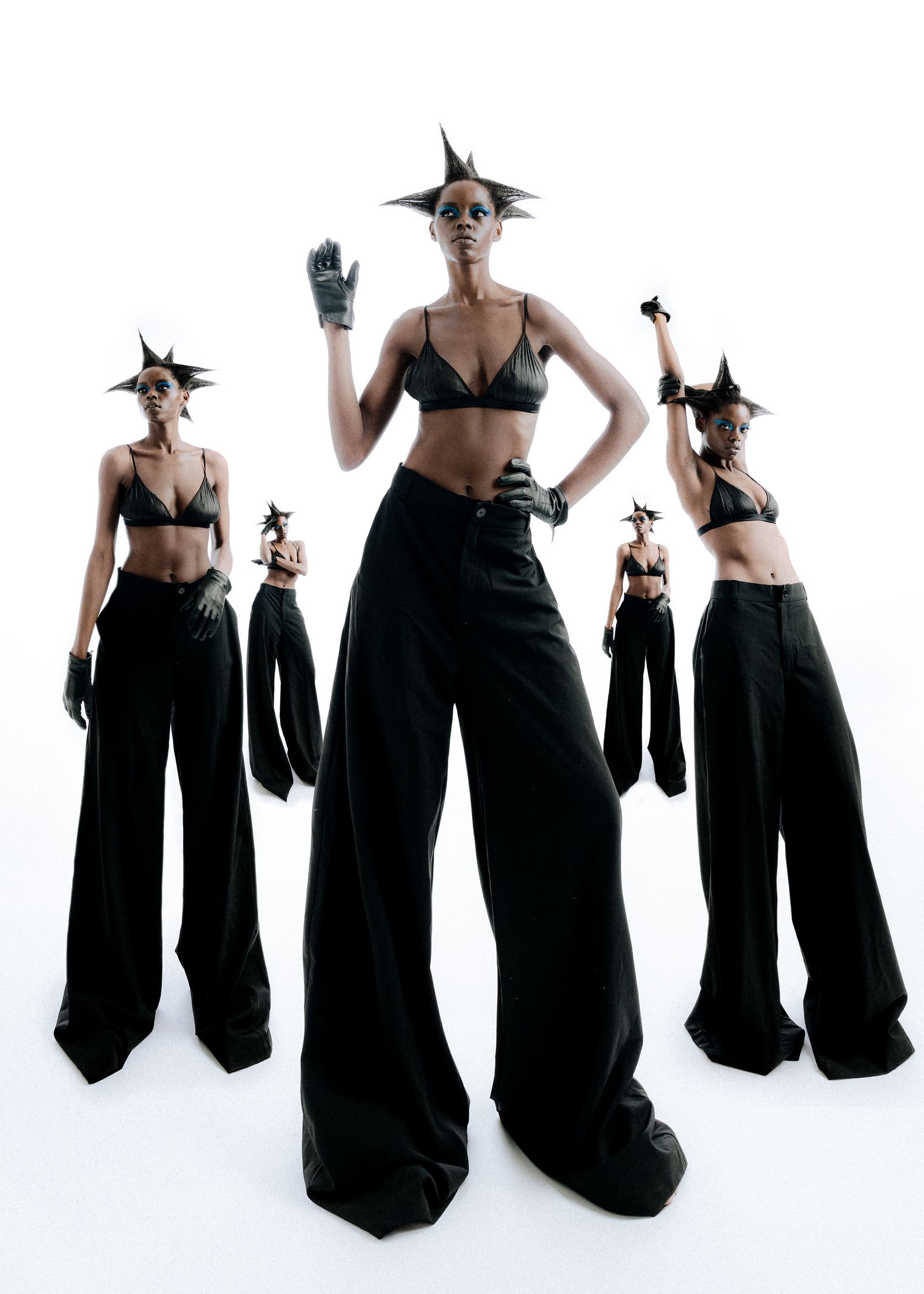 a fashion editorial of a  group of women in black pants posing in front of a white background