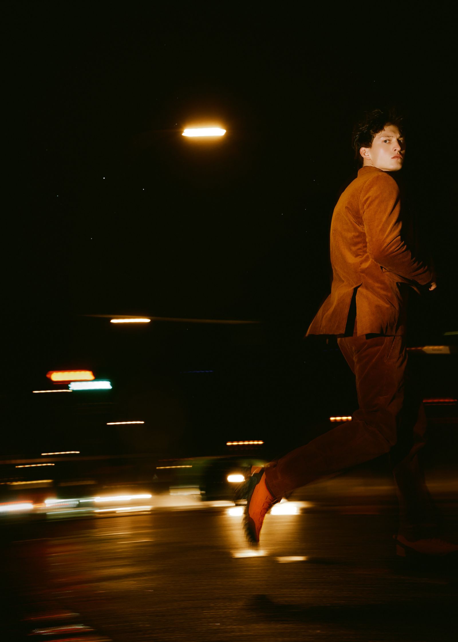 a man in an orange suit running down the street at night