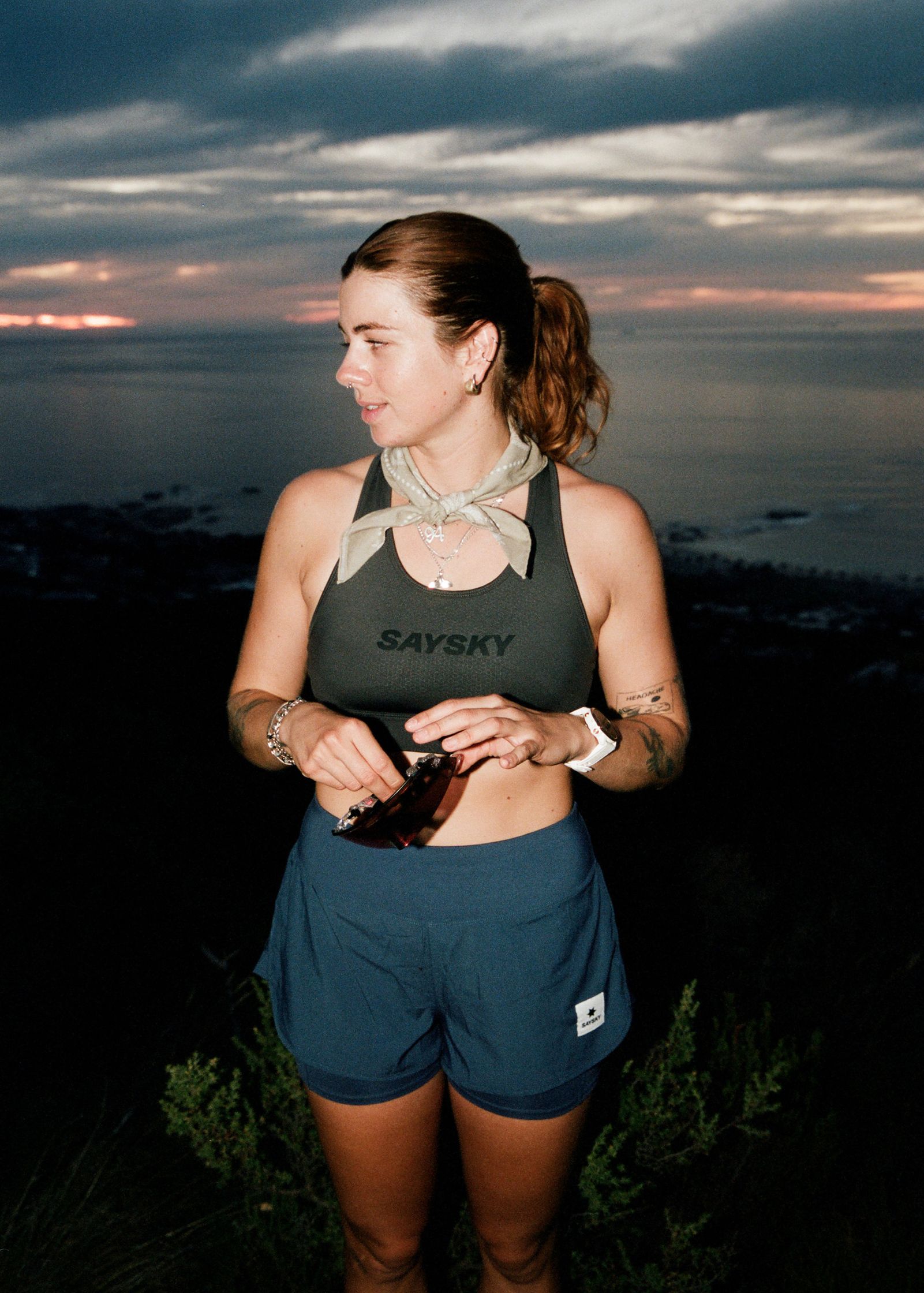 a woman standing in front of a mountain at sunset