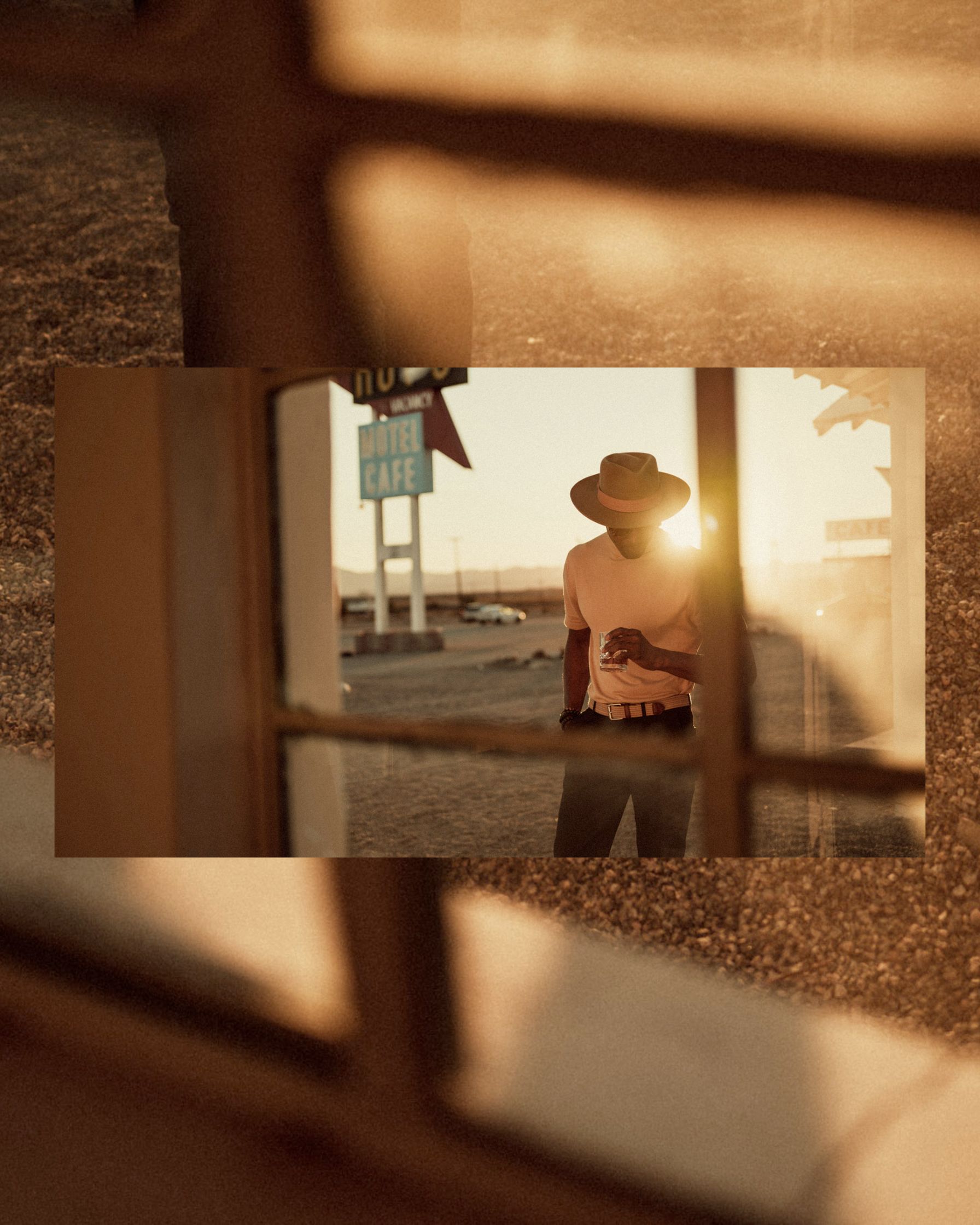 a man in a hat standing in front of a window