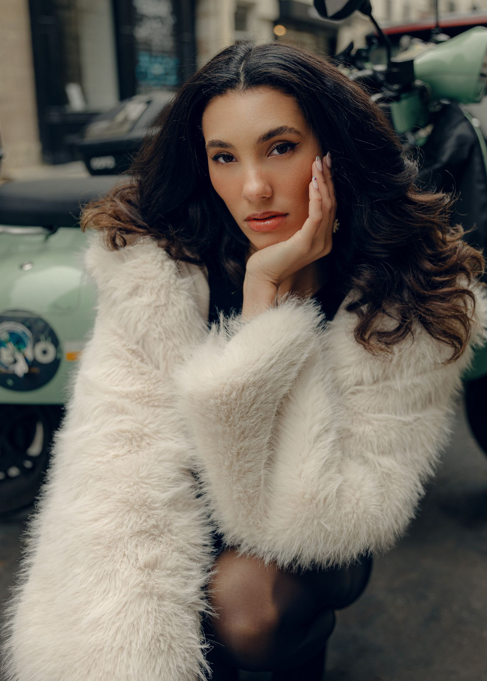 a woman in a white fur coat posing in front of a scooter