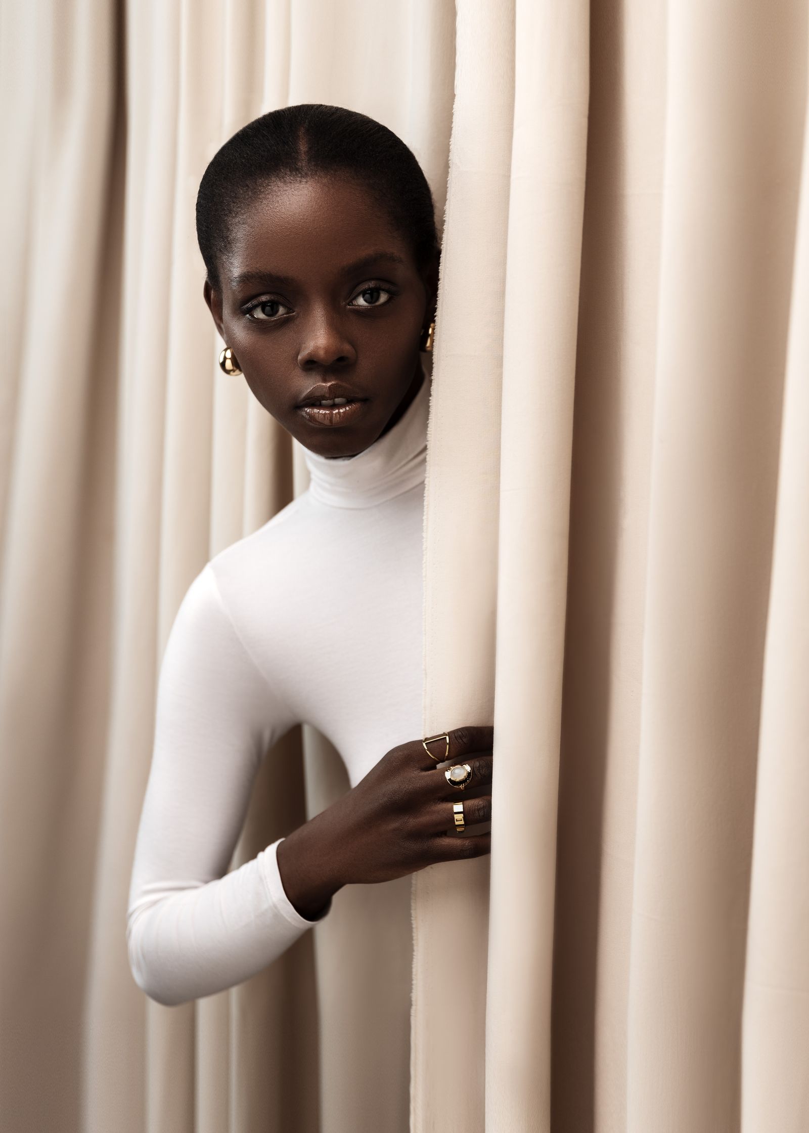 a black woman peeking out of a curtain