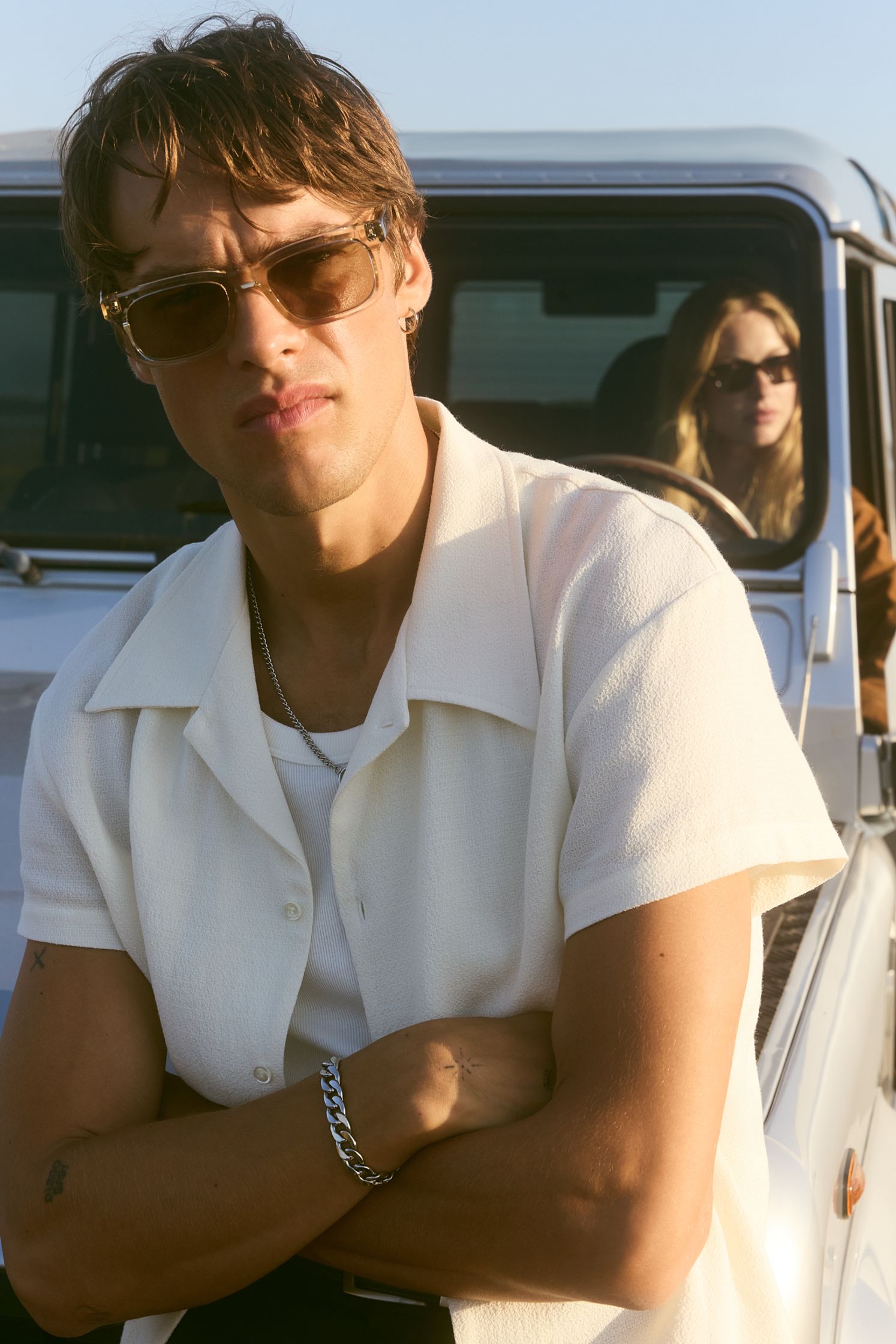 a man and woman in sunglasses standing next to a jeep