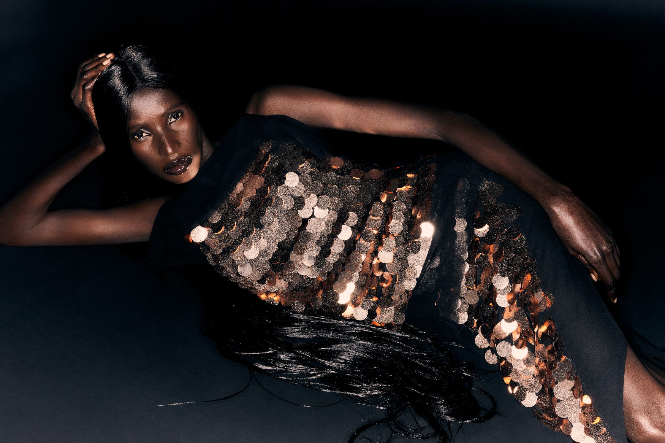 a woman in a black dress laying on a black background