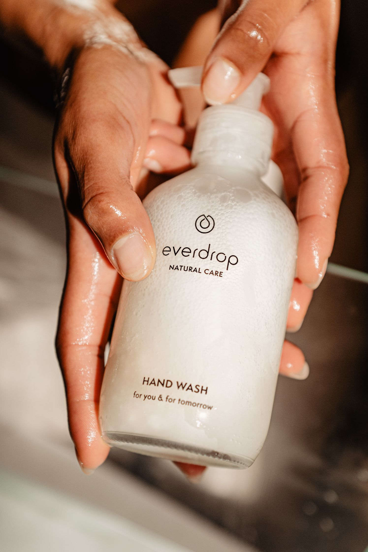 a person is holding a bottle of everdrop hand wash