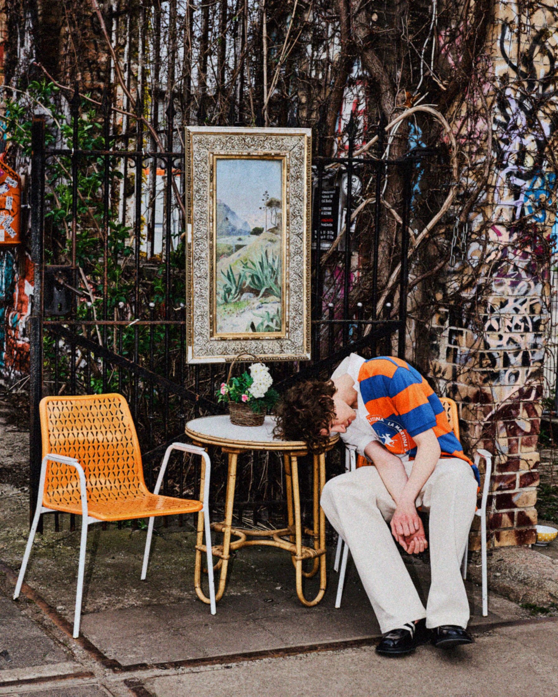 a man sleeping on a chair in front of a painting