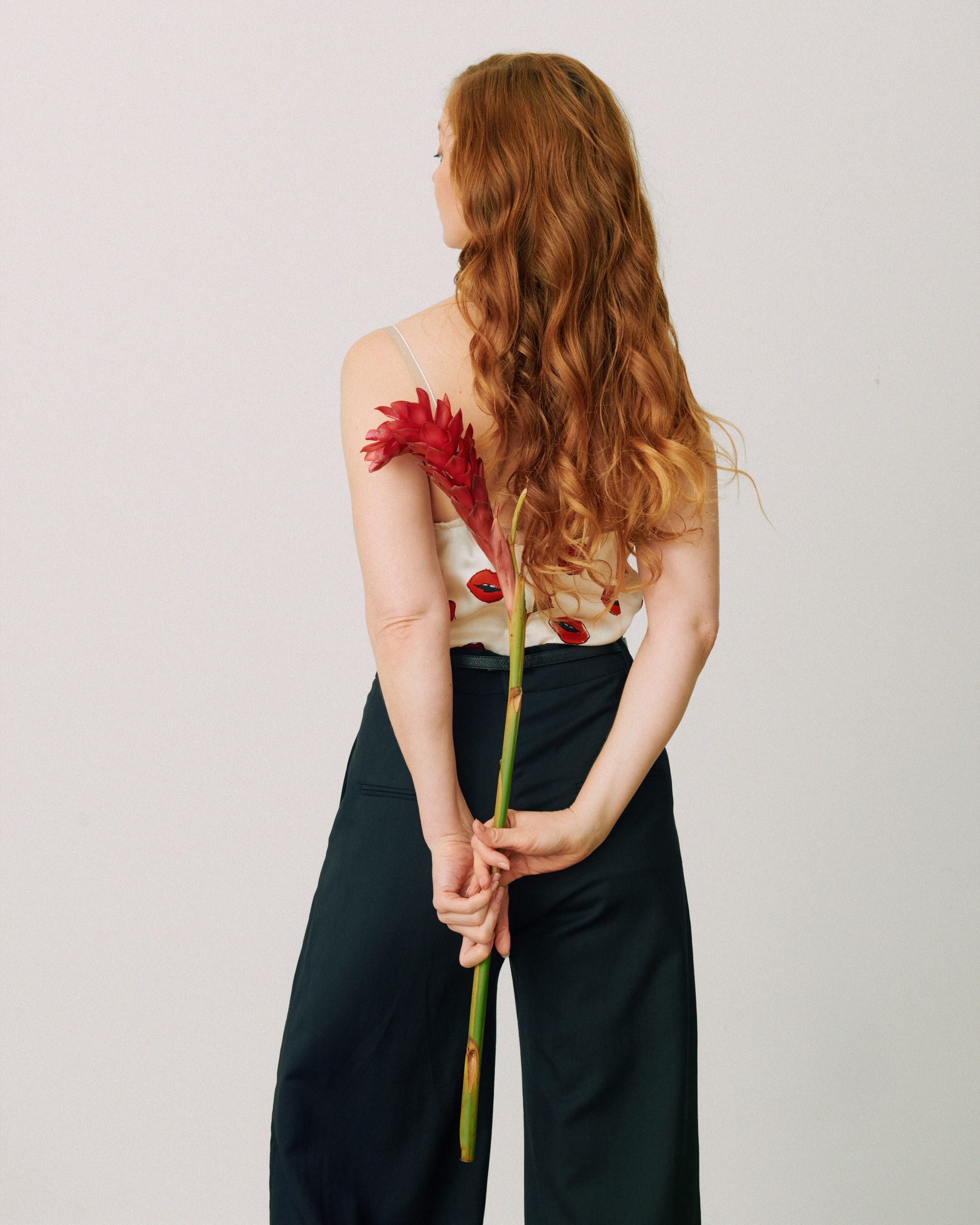 Pheline Roggan in black wide leg pants holding a flower