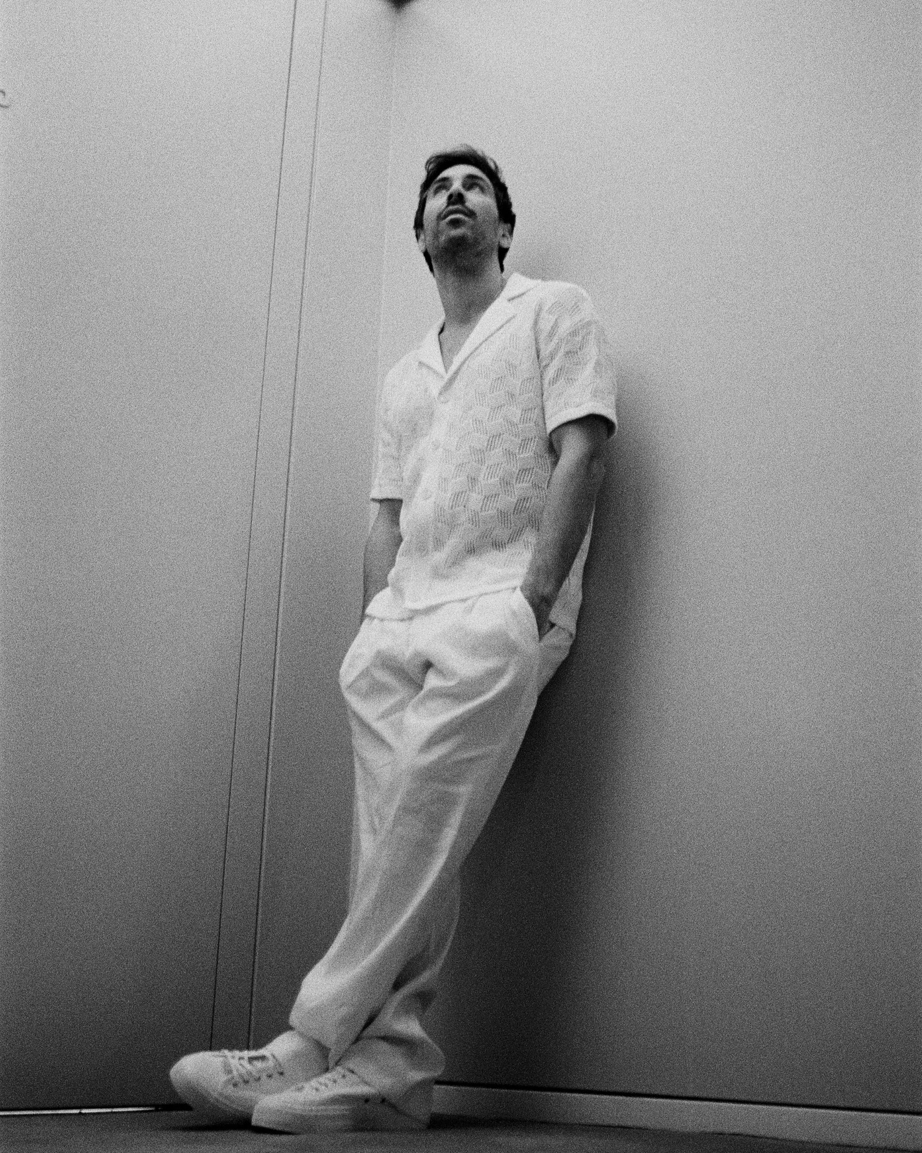 Max Giesinger leaning against a wall in white pants